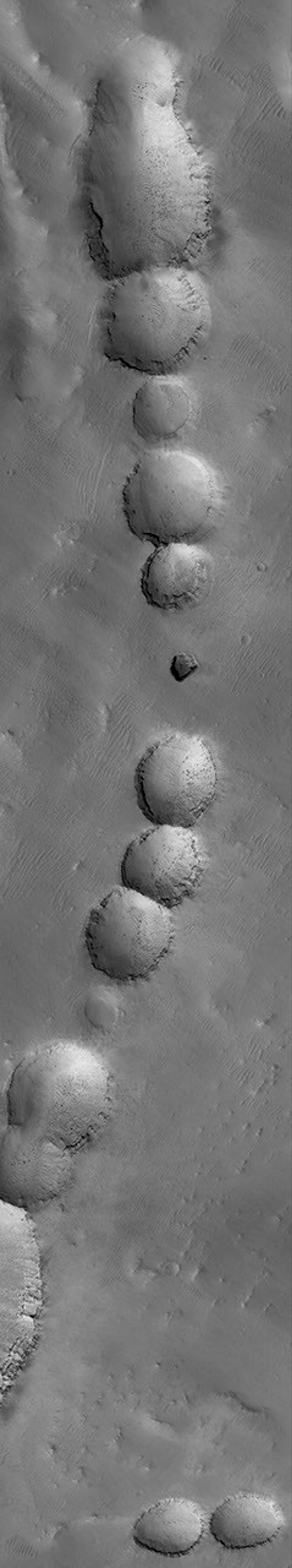 This image from NASA's Mars Global Surveyor shows a portion of a pit chain on the lower, northern flank of the giant martian volcano, Arsia Mons.