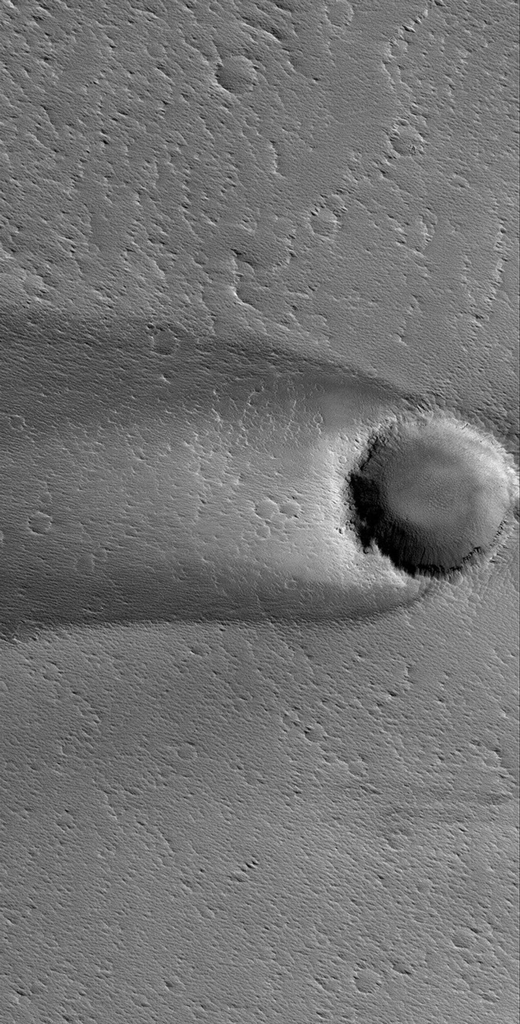 NASA's Mars Global Surveyor shows a wind streak formed in the lee of an impact crater in western Daedalia Planum on Mars.