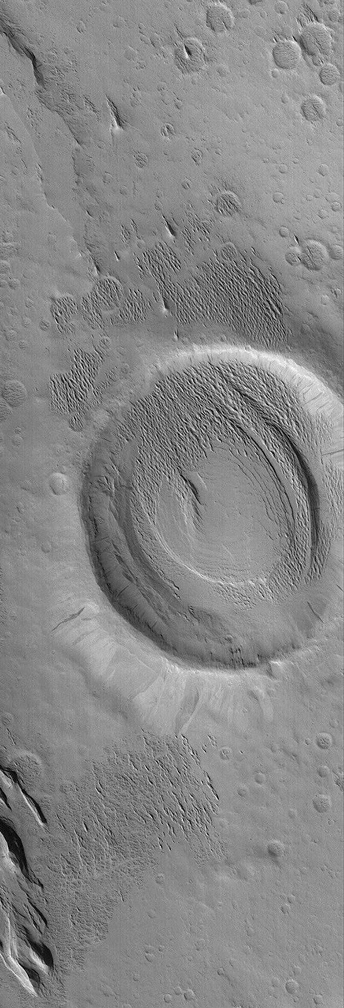NASA's Mars Global Surveyor shows a crater and adjacent terrain that have been exhumed from beneath a wind-eroded material. The sharp, pointy ridges inside and immediately adjacent to the crater are evident.