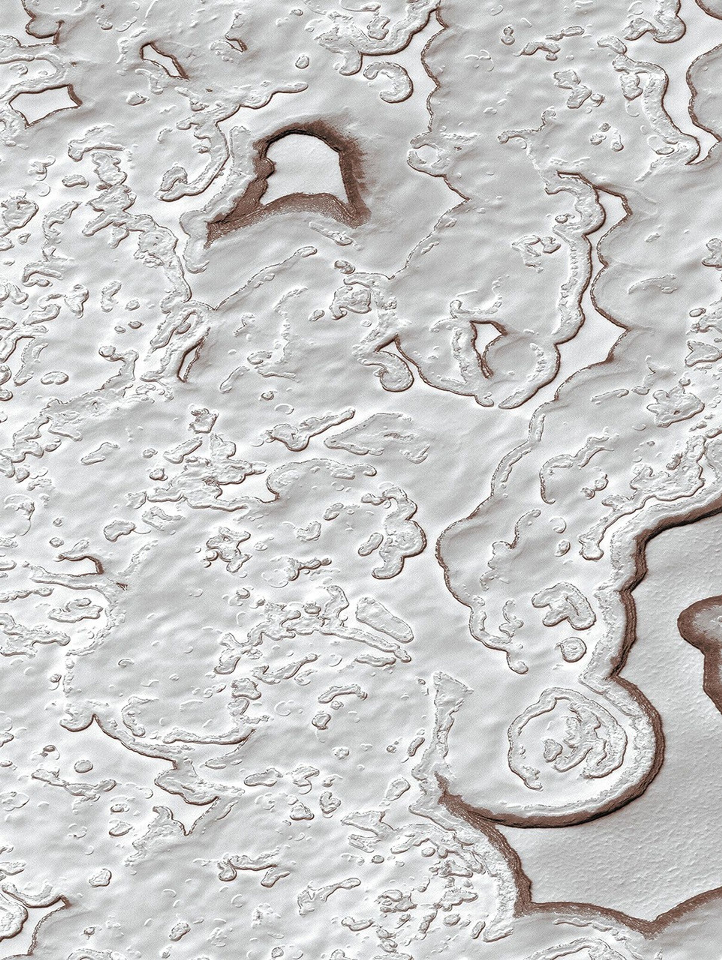 NASA's Mars Global Surveyor shows a landscape of Mars' south polar residual cap dominated by layered, frozen carbon dioxide ('dry ice') that has been eroded into a variety of pits, troughs, buttes, and mesas.