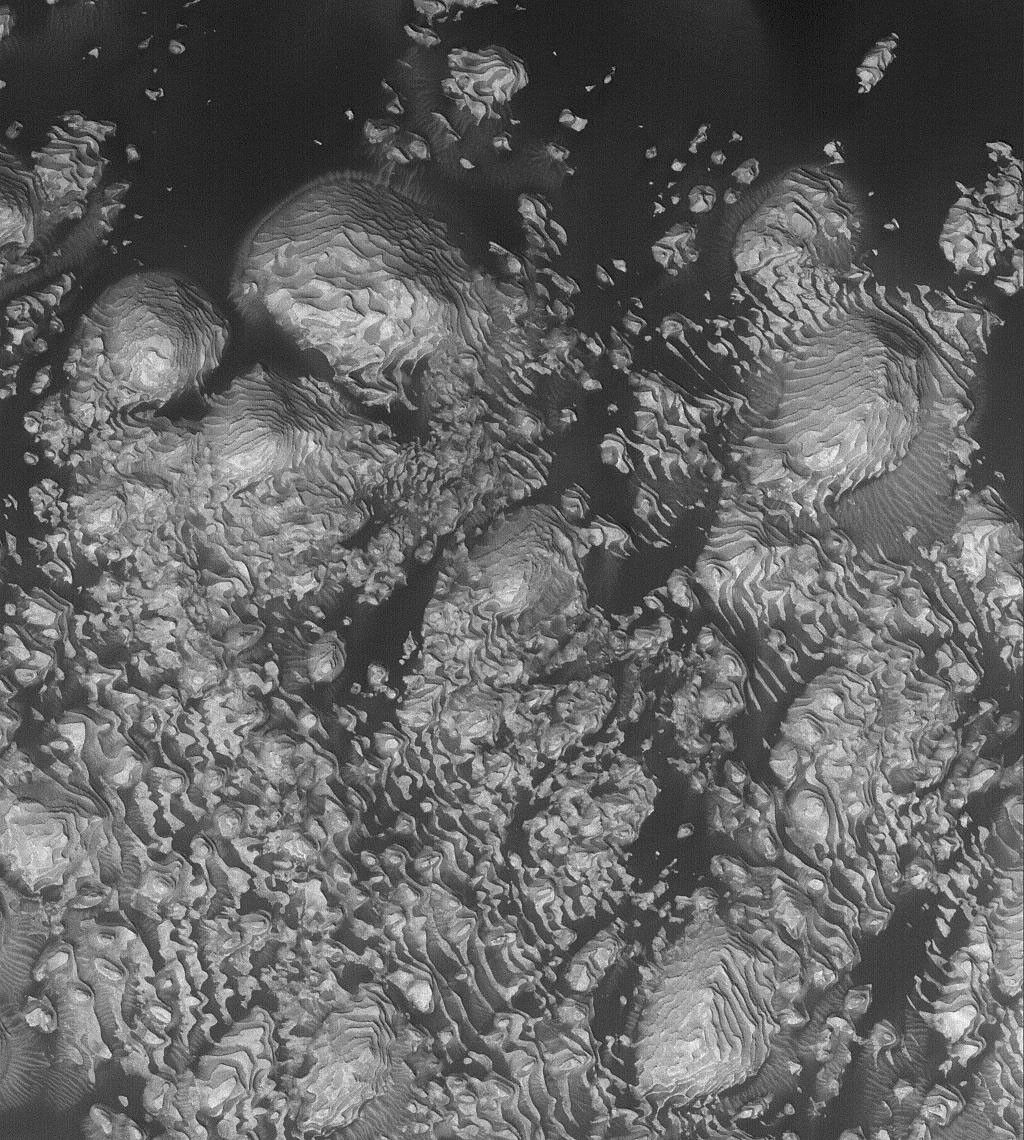 NASA's Mars Global Surveyor shows ight-toned, layered, sedimentary rock outcrops in an unnamed crater on Mars. Dark, windblown sand enhances the contrast in this view.