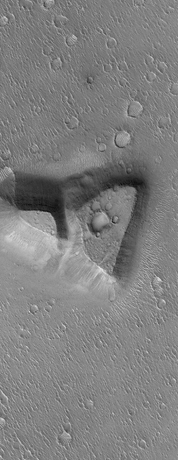 NASA's Mars Global Surveyor shows a mesa in northeastern Isidis Planitia. The mesa might be a remnant of terrain that once more extensively covered this region on Mars.