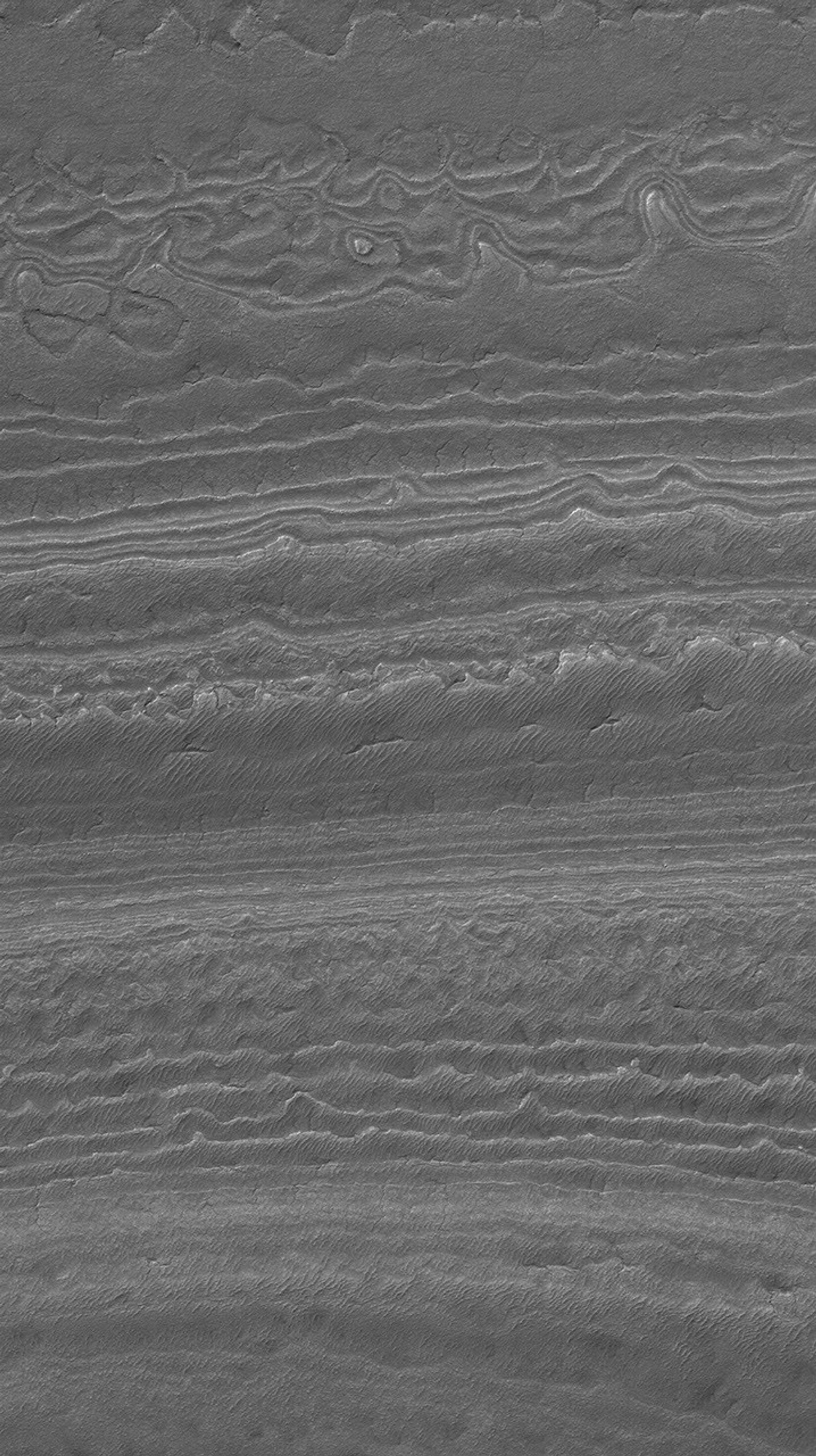 NASA's Mars Global Surveyor shows an eroded landscape in the south polar region of Mars. Layered material has been exposed to create a complex pattern of steps and low, isolated mesas.