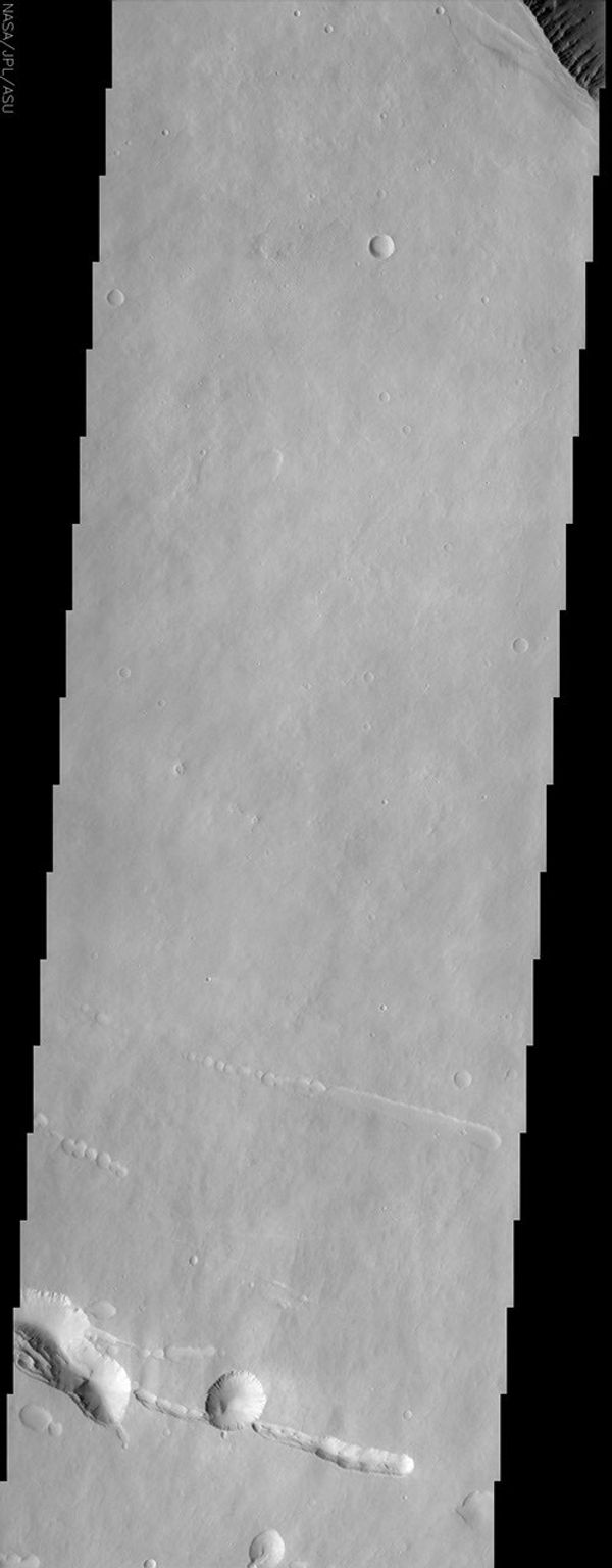 At the top right of this NASA Mars Odyssey image, the rim of the caldera of Pavonis Mons, one of four exceptionally large volcanoes in the Tharsis region, is barely visible with steep cliffs formed by the collapse of a portion of the volcano's summit.