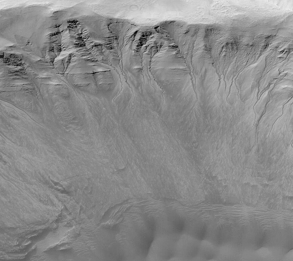 NASA's Mars Global Surveyor shows gullies that occur on the layered north wall of a crater in Newton Basin on Mars. Dark sand dunes are visible.