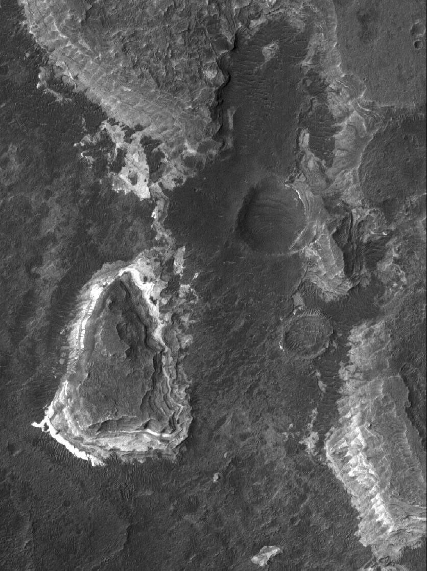 NASA's Mars Global Surveyor shows light-toned, layered, sedimentary rocks exposed by the fluids that carved the Ladon Valles system in the Erythraeum region of Mars.
