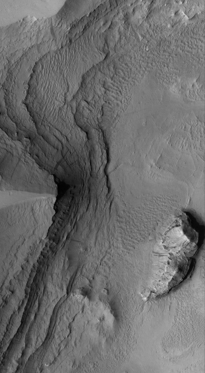 NASA's Mars Global Surveyor shows layered sedimentary rocks exposed by erosion, then mantled by dust, in Tikhonravov Crater in central Arabia Terra on Mars.
