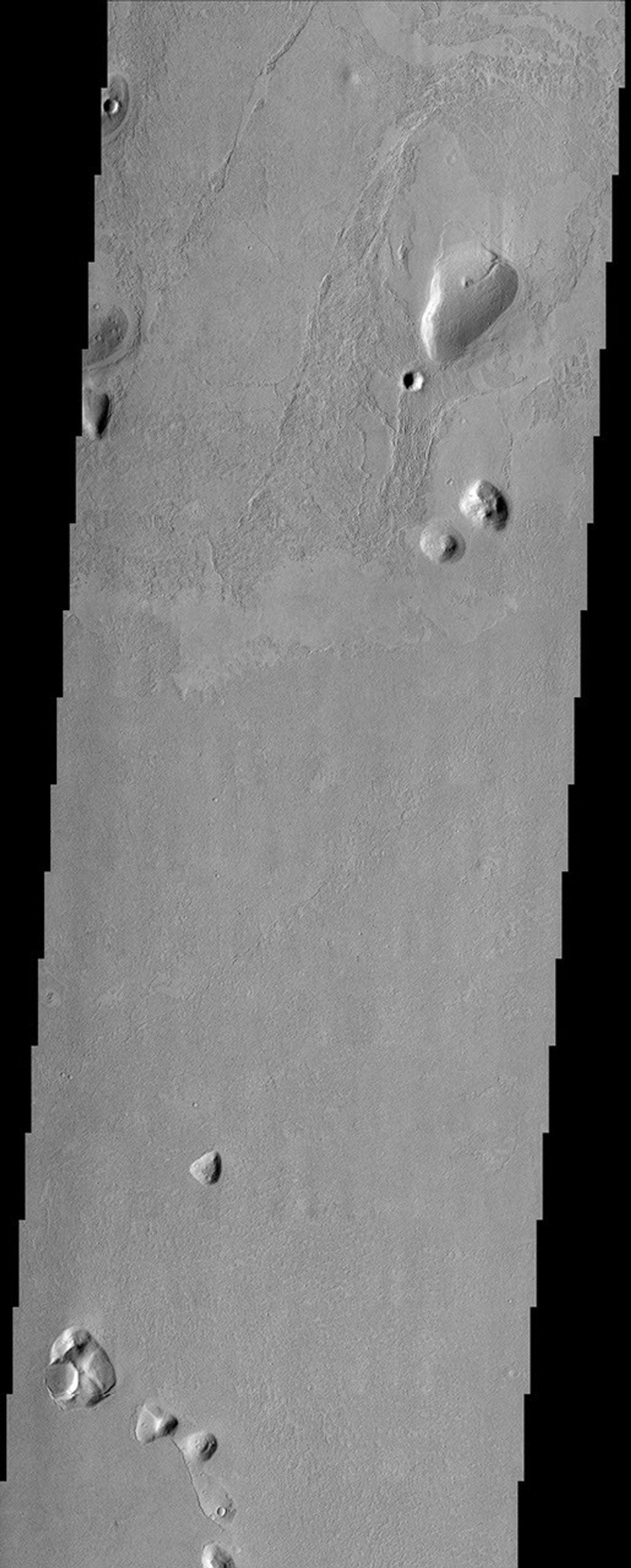 Islands of older high-standing terrain rise above a sea of relatively young, platy lava flows between two of the largest volcanoes in the solar system in this image from NASA's Mars Odyssey spacecraft.