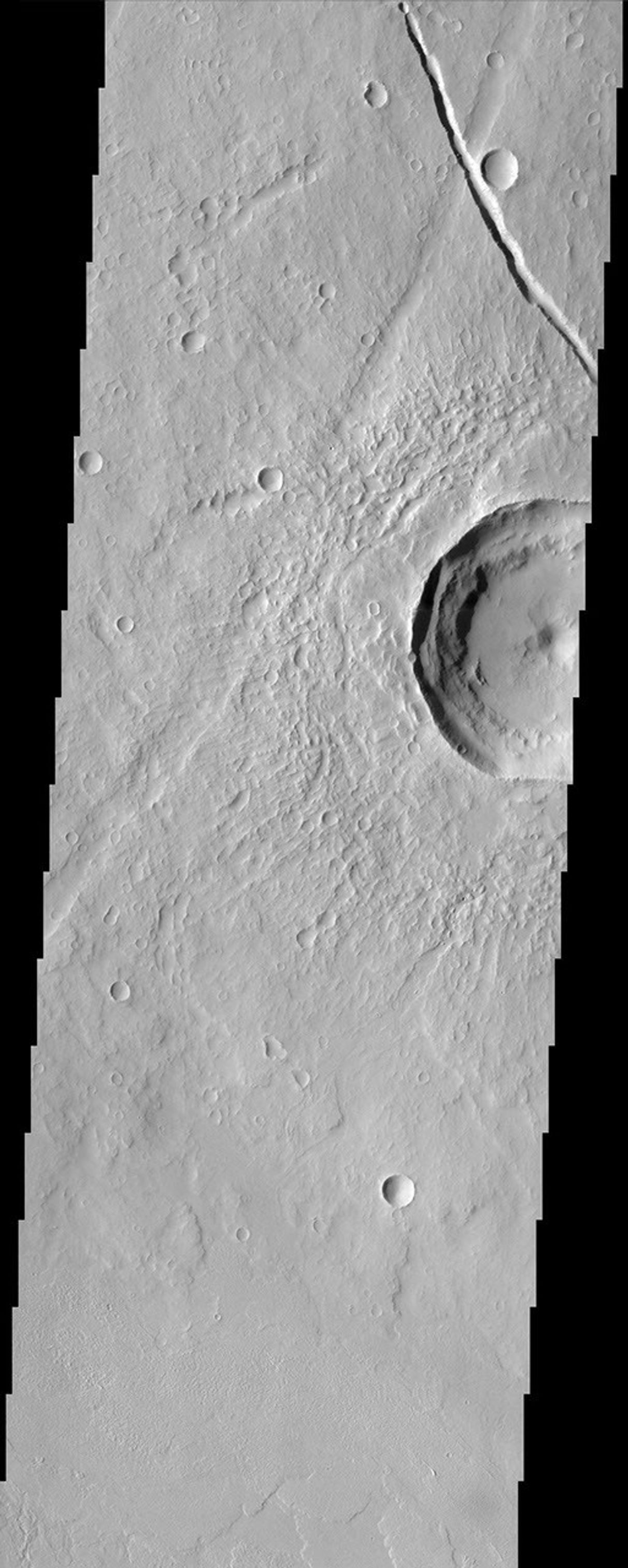 This area of Mars imaged by NASA's Mars Odyssey shows a wonderful example of relative geologic dating. Ancient lava flows and escarpments are mantled by younger impact ejecta, which was cut by a younger graben and resurfaced by smaller impact craters.