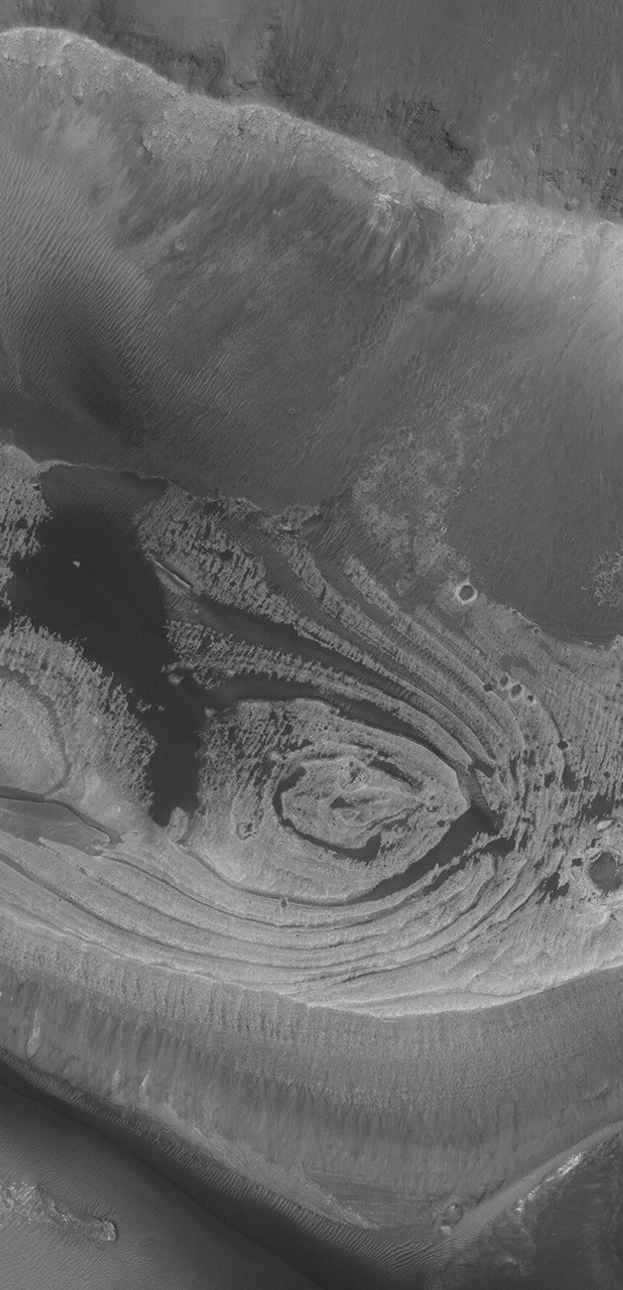 NASA's Mars Global Surveyor shows light-toned, layered rock outcrops found in eastern Candor Chasma, part of the vast Valles Marineris trough system on Mars.
