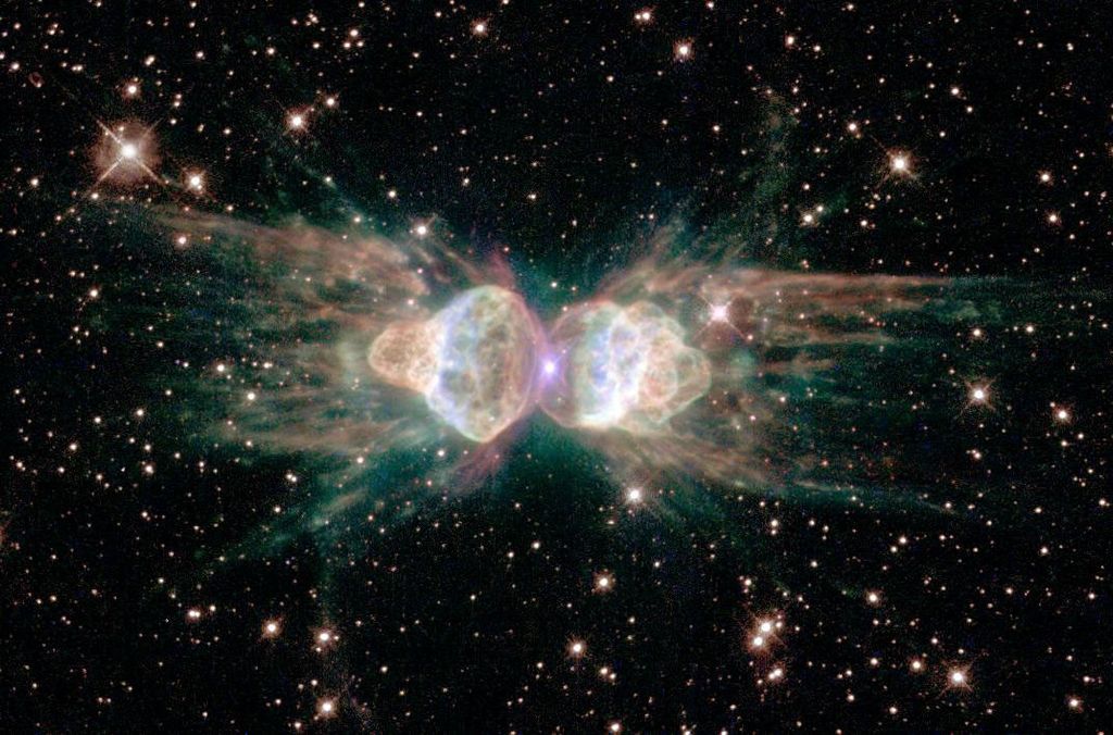 A dark starfield appears around an unusually shaped nebula. The nebula has two main lobes on the left and the right and may seem to resemble an ant.