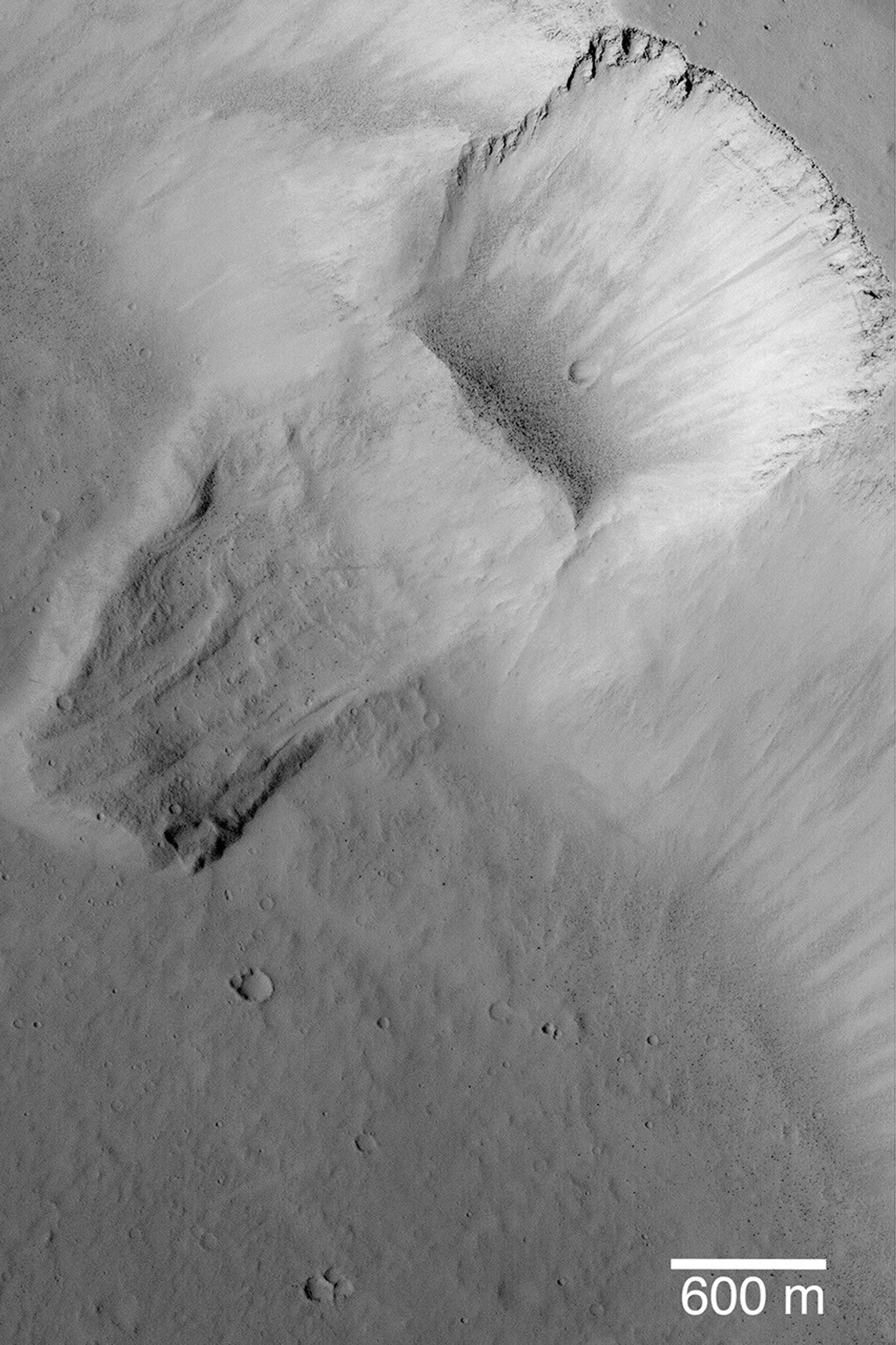 NASA's Mars Global Surveyor shows a scar left by a landslide revealing layers in the bedrock at the top the slope and shows a plethora of dark-toned, house-sized boulders that rolled down the slope and collected at the base of the landslide scar.