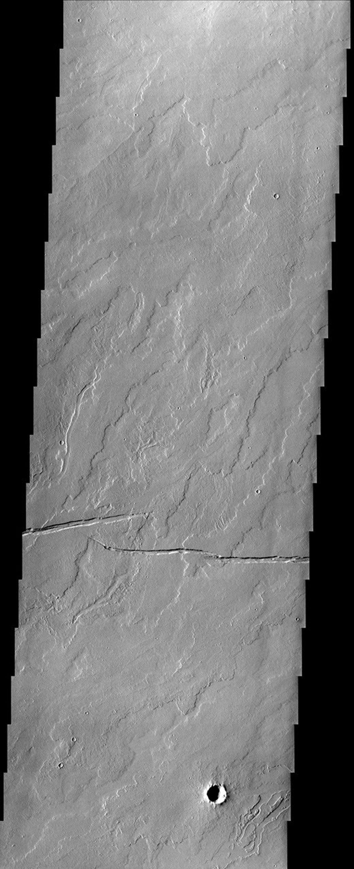In this image from NASA's Mars Odyssey spacecraft, numerous lava flows and fossae (cracks) are visible in a region of Mars located southeast of Olympus Mons. There is also a hint that water may have possibly flowed in the region.