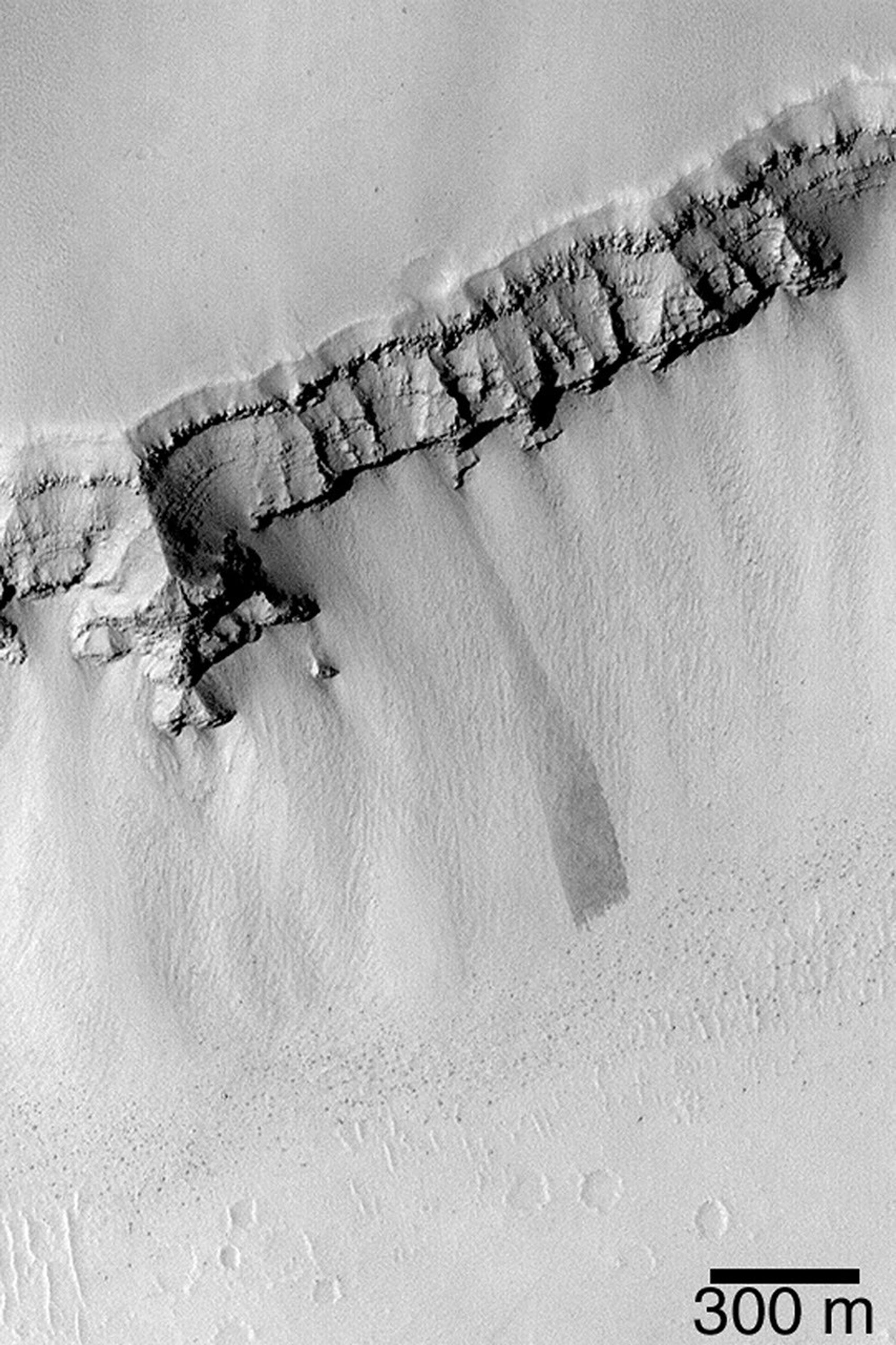 NASA's Mars Global Surveyor shows the wall of a trough in the Zephyrus Fossae region, west of the Elysium Rise on Mars. Talus covers the lower portions of the wall; many large boulders, most of which are seen as dark dots at the base of the slope.