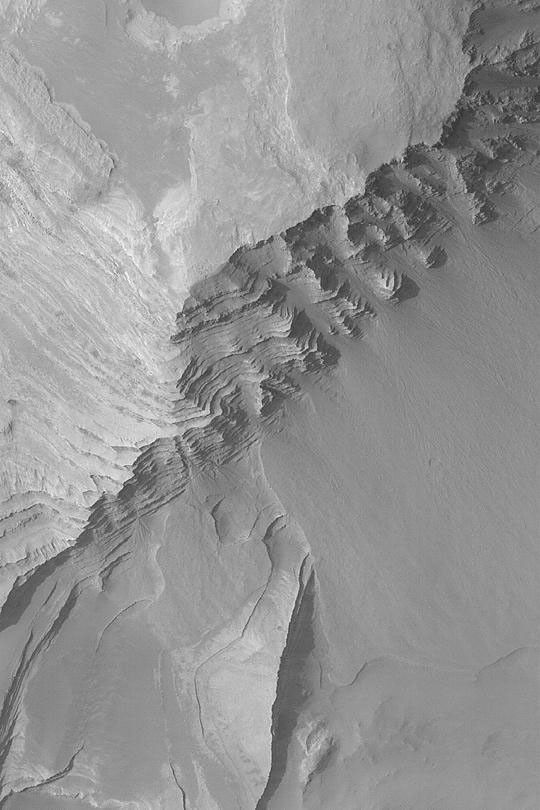 NASA's Mars Global Surveyor shows some of the layer outcrops in Terby Crater on Mars. Fans of debris have eroded from the steep, layered slopes in some places.
