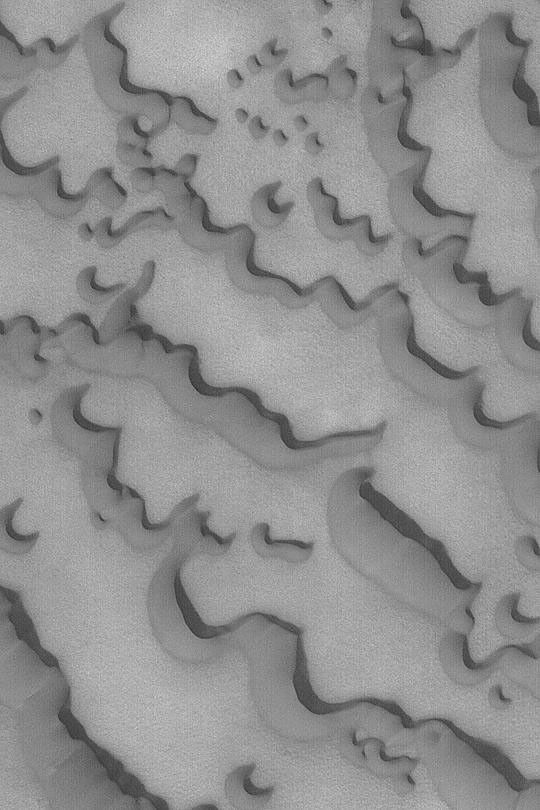 NASA's Mars Global Surveyor shows martian north polar ice cap surrounded by fields of dark, windblown sand dunes.