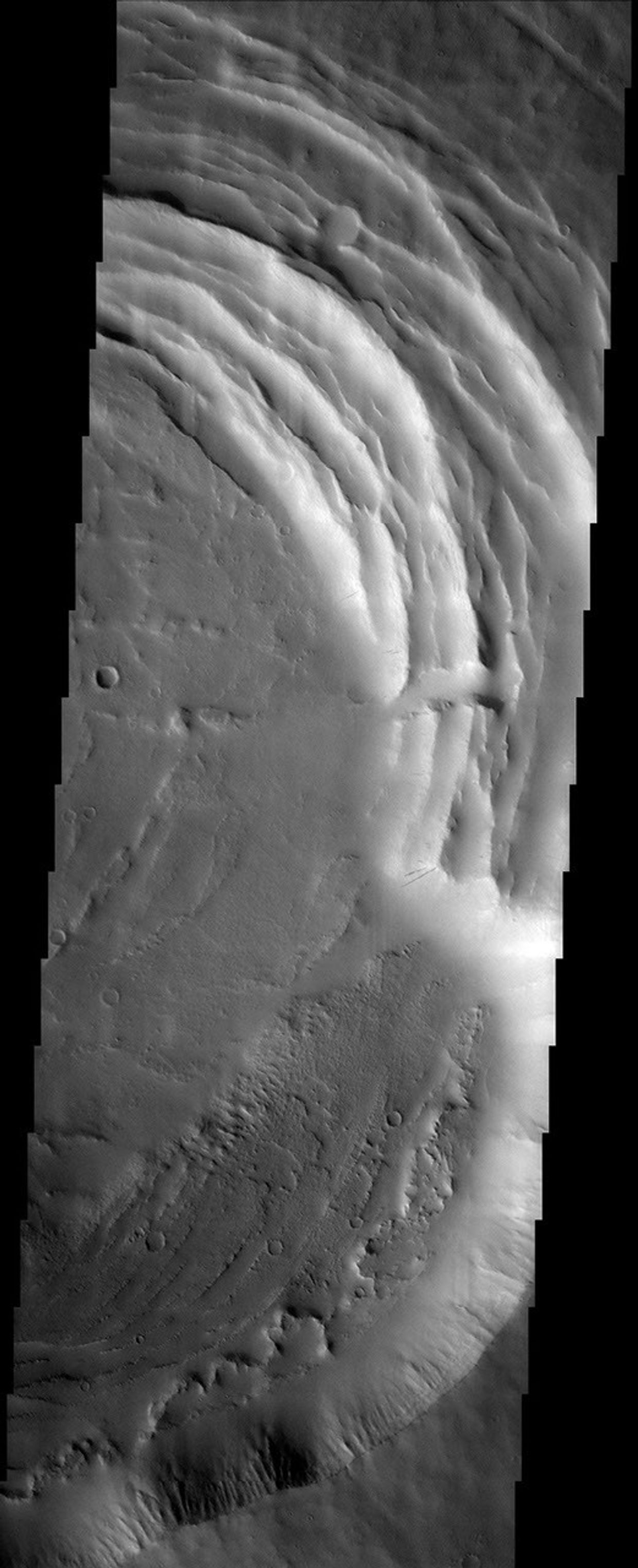 The small Tharsis volcano called Biblis Patera is nearly lost amongst its gigantic neighbors. The gaping caldera of Biblis Patera shows evidence for multiple episodes of collapse. This image was captured by NASA's Mars Odyssey spacecraft in October 2003.