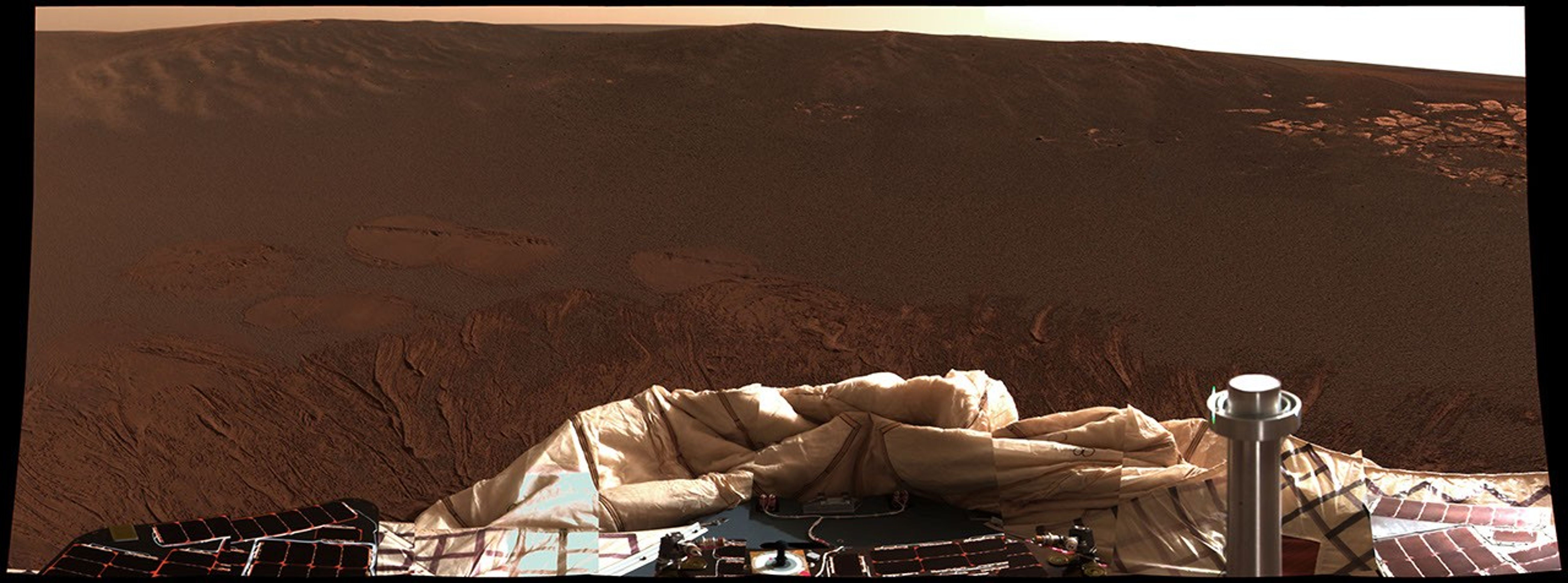 The interior of a crater in red hues showing a mixture of coarse gray grains and fine reddish grains surrounding NASA's Mars Exploration Rover Opportunity at Meridiani Planum on Mars;