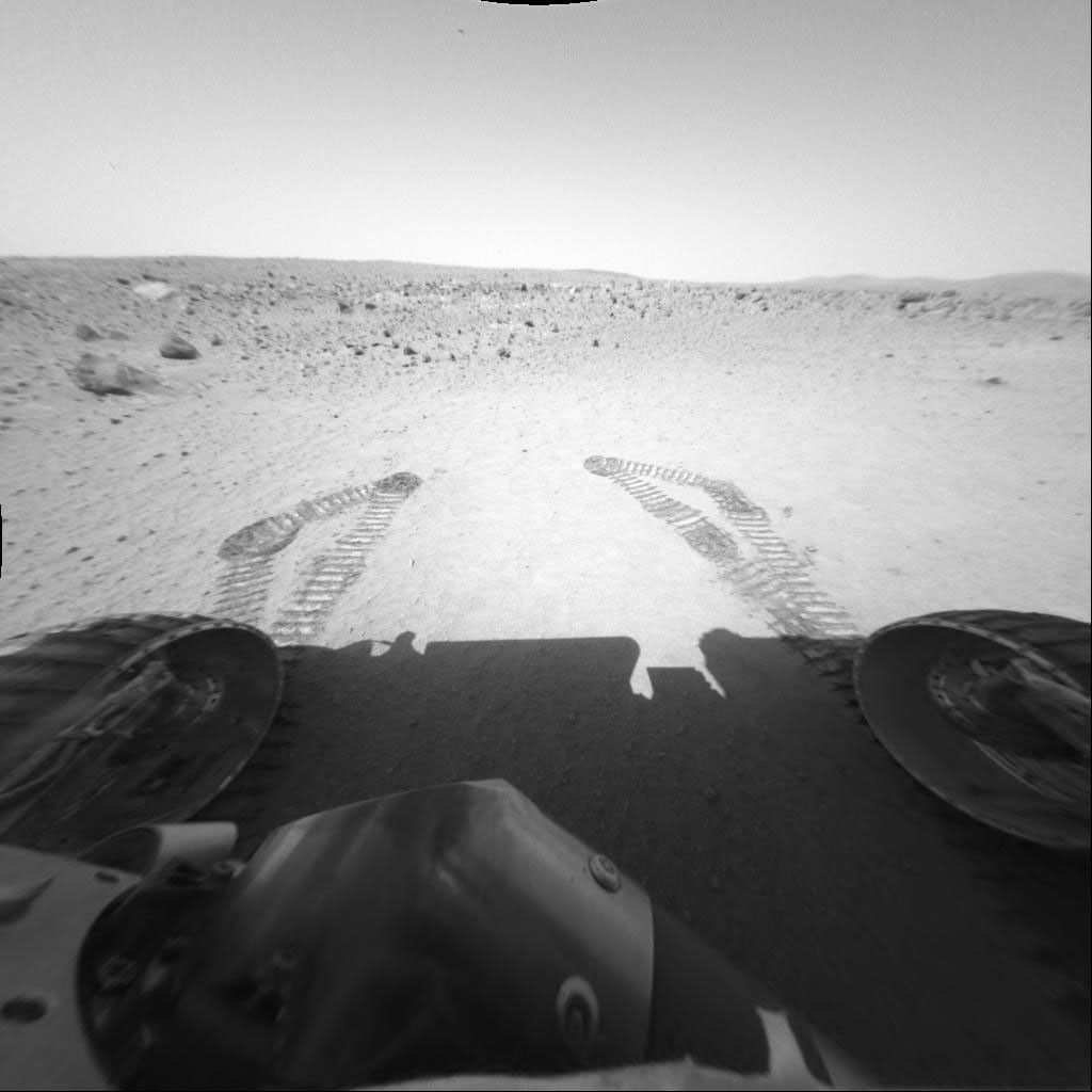 NASA's Mars Exploration Rover Spirit shows a circular depression, dubbed 'Laguna Hollow,' most likely formed by a small impact. The rover's tracks are seen in front of the rover.