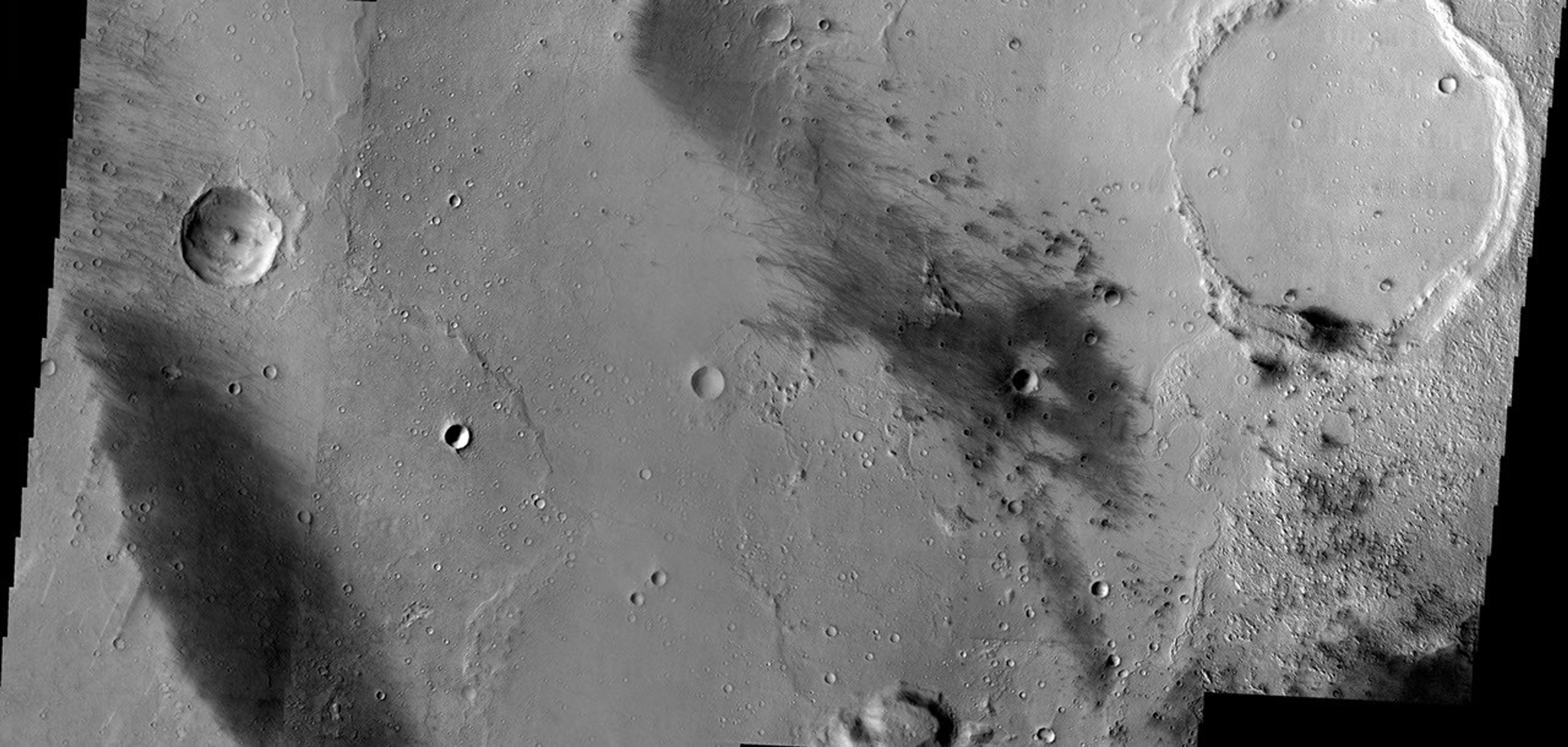 This image from NASA's 2001 Mars Odyssey released on Jan 3, 2004 shows dark streaks where wind has either scoured off the brighter martian dust or has covered it up by sand in Gusev Crater, the site of Spirit's landing.