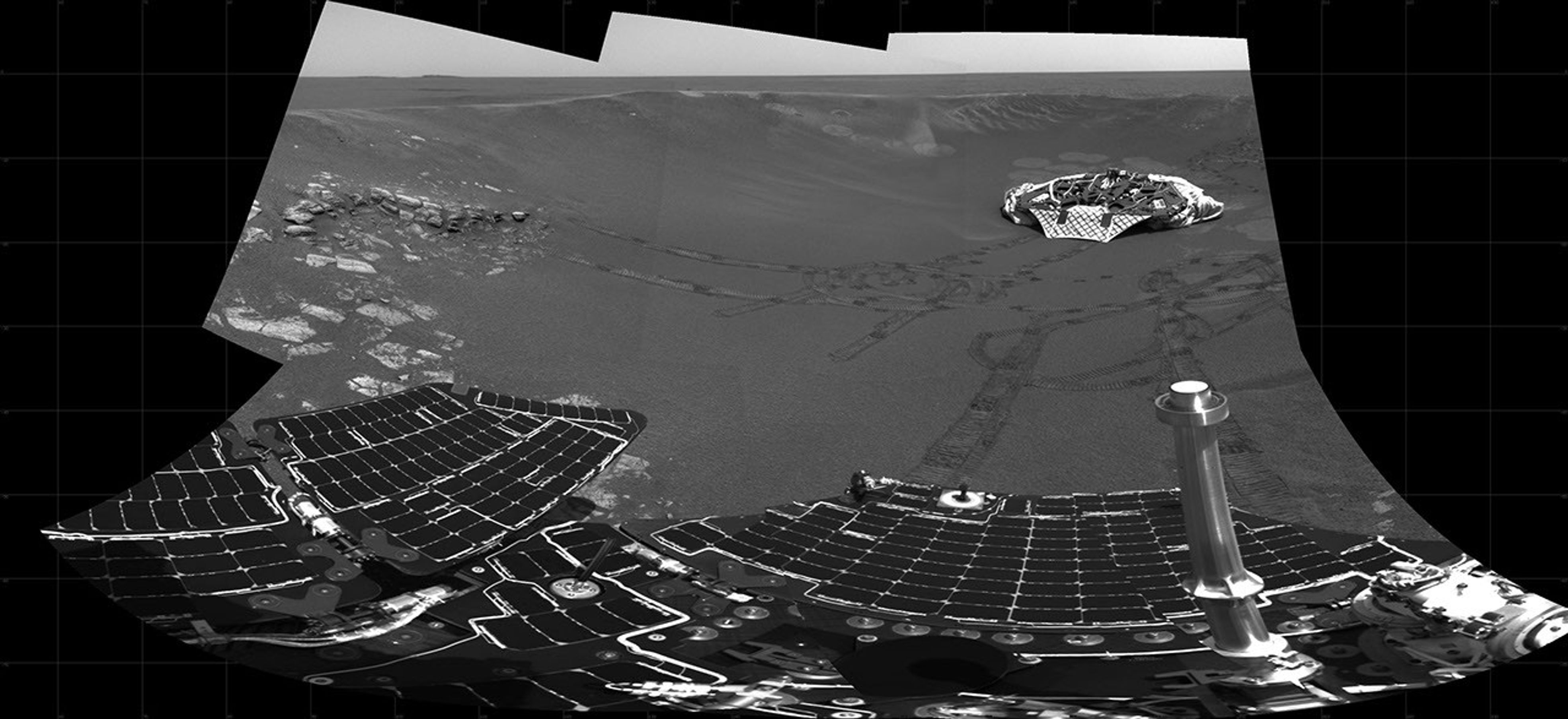 This partial panoramic image from NASA's Mars Exploration Rover Opportunity shows the lander in the center of the crater at Meridiani Planum, Mars. In view are plains outside the crater, the rover tracks, and the airbag bounce marks behind the lander.