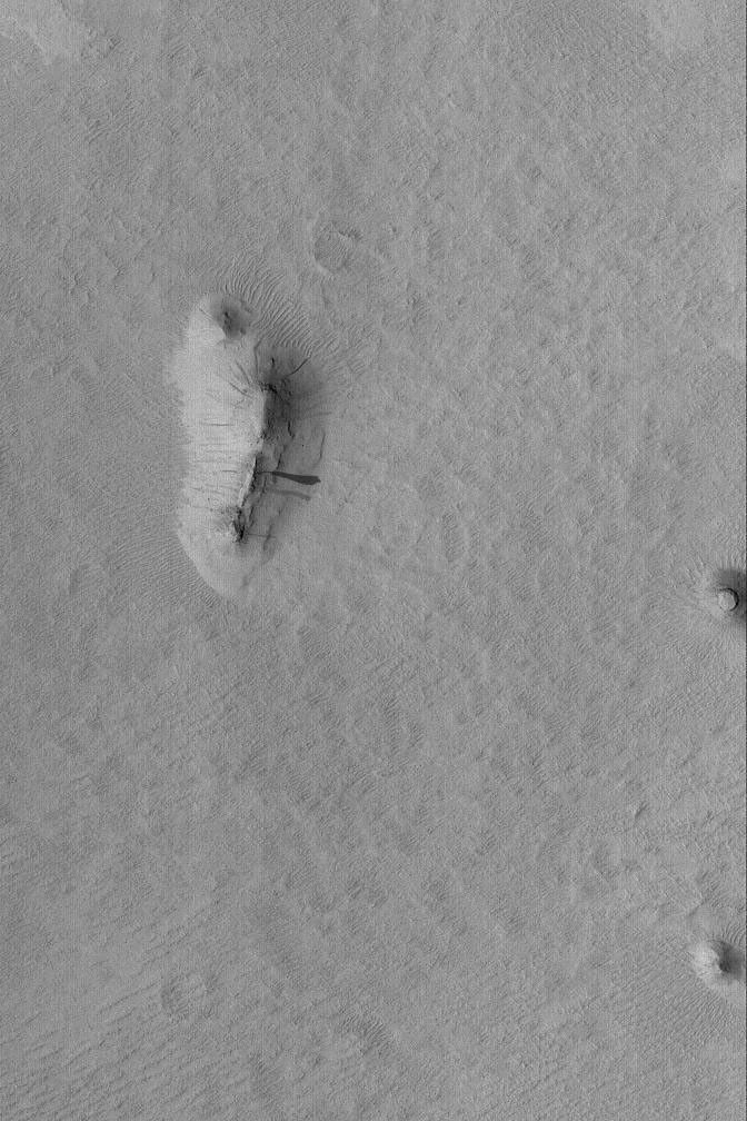 NASA's Mars Global Surveyor shows three small buttes in the Memnonia Sulci region of Mars. The buttes are remnants of formerly more extensive layered rock that once covered the region.