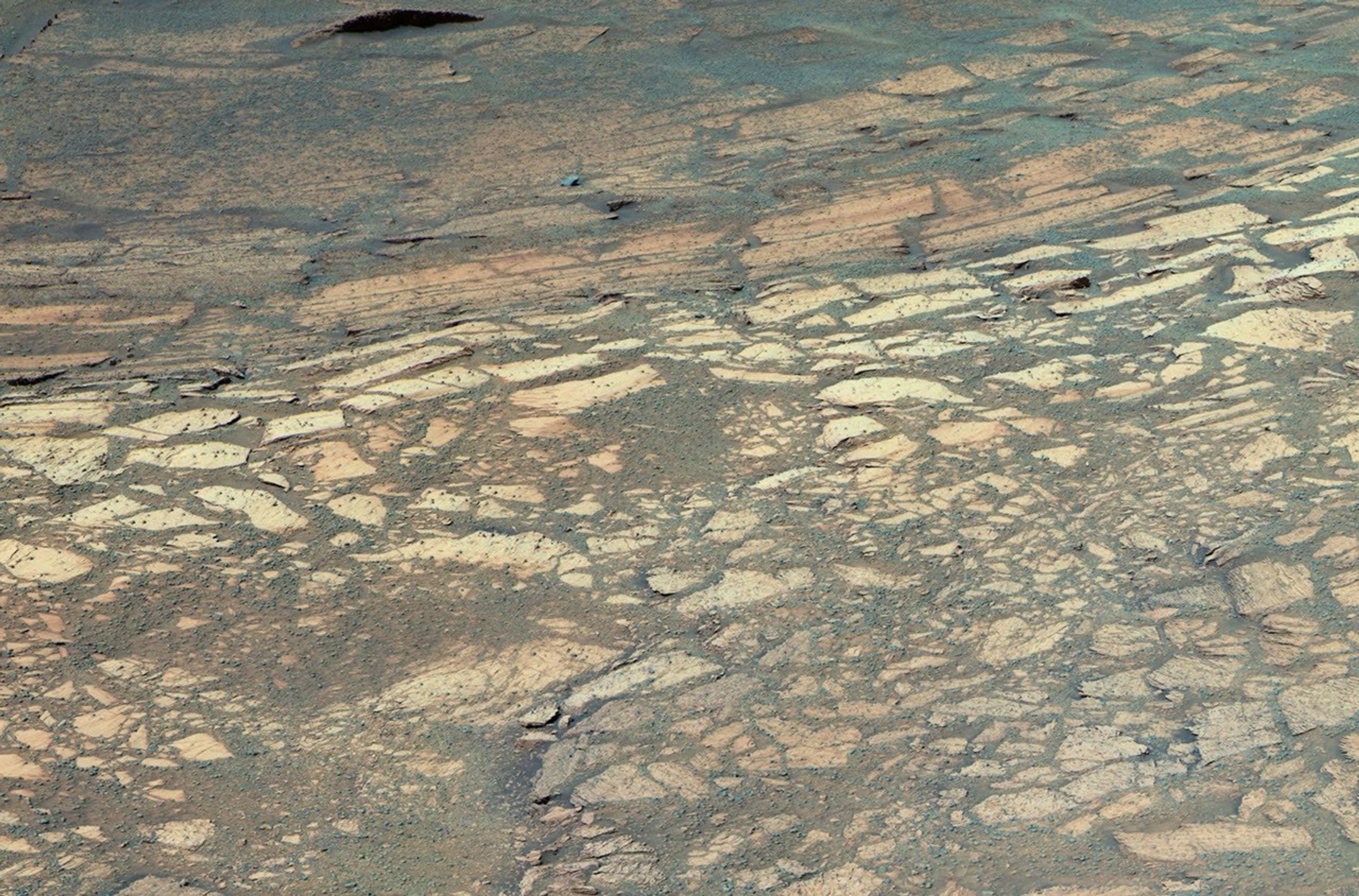 This image from NASA's Mars Exploration Rover Opportunity shows a hole it drilled into a flat rock dubbed 'Tennessee' on Mars. At least three distinct bands of rock visible in front of the rover.