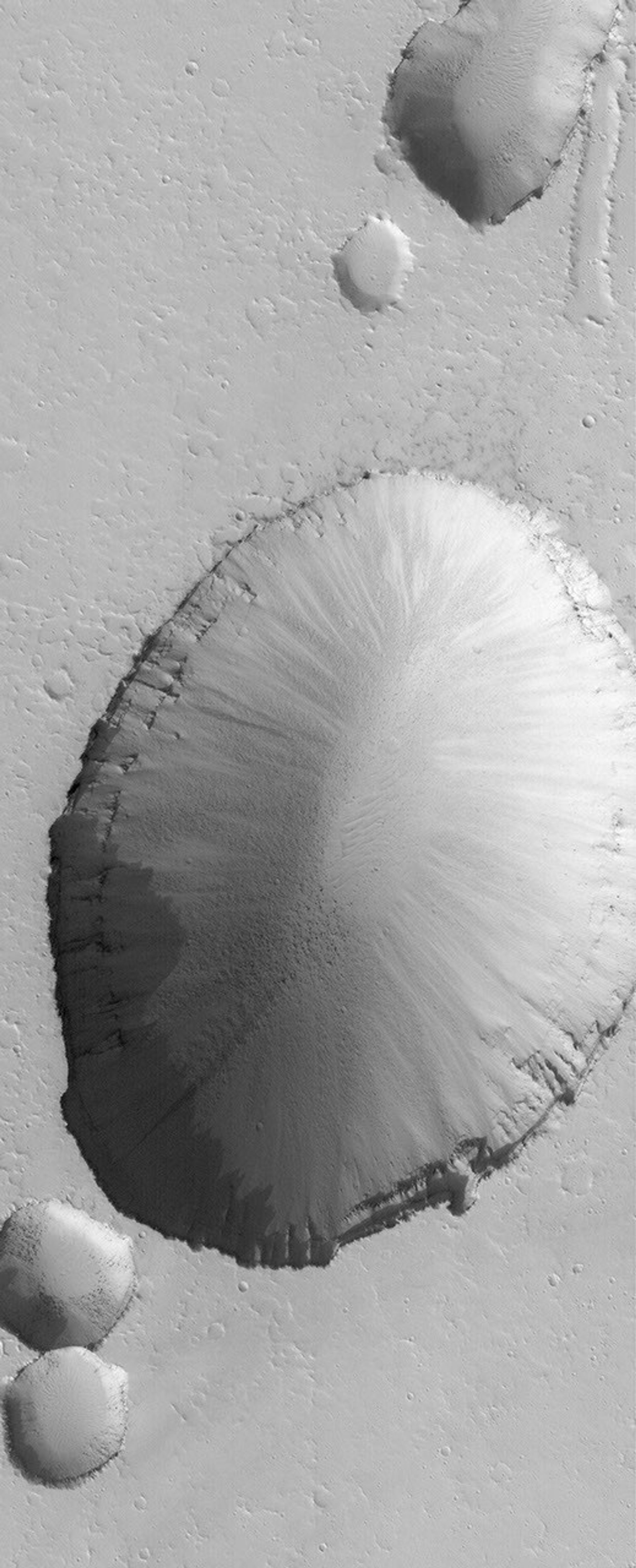 NASA's Mars Global Surveyor shows a large collapse pit (and portions of several smaller pits) in the Tractus Fossae portion of the Tharsis region of Mars.