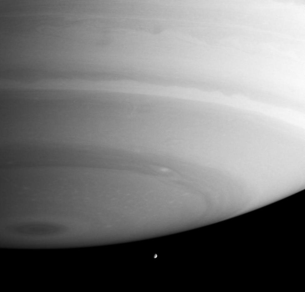 Saturn's massive atmosphere appears poised to crush little Enceladus in this image captured by NASA's Cassini spacecraft.