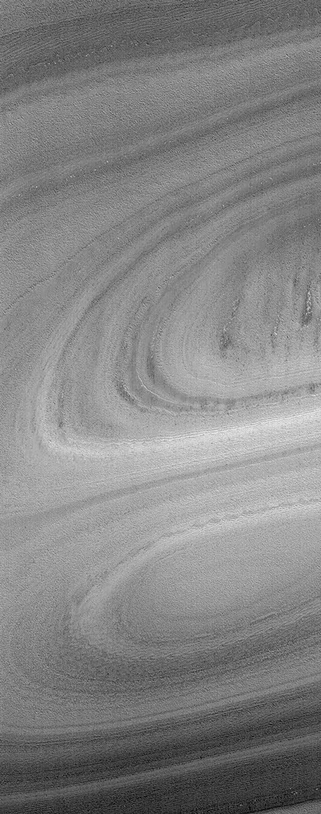 NASA's Mars Global Surveyor shows exposures of Mars' north polar layered material, perhaps composed of a mixture of dust and ice, in the form of a hill and an adjacent depression.