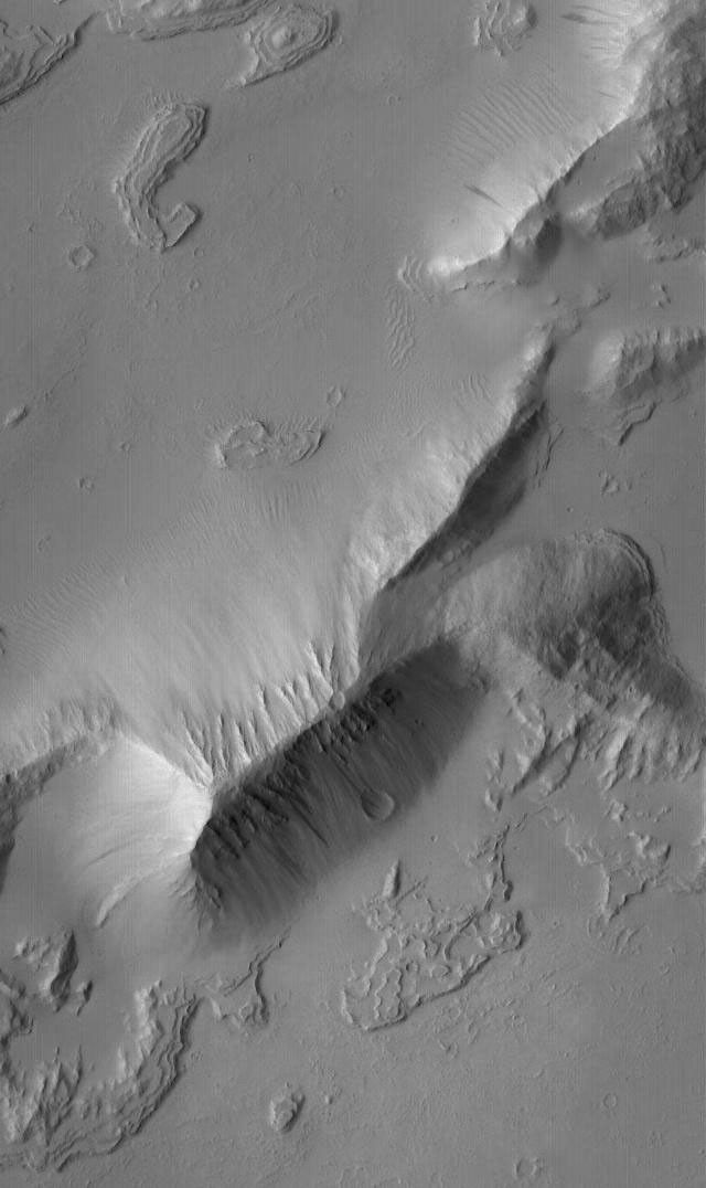 NASA's Mars Global Surveyor shows detailed layered rock features, mantled by fine dust, in the Sulci Gordii ridged region east of Olympus Mons on Mars.