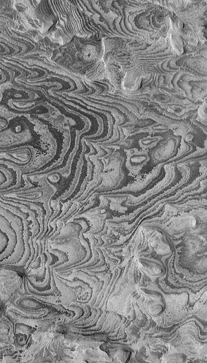 NASA's Mars Global Surveyor shows alternating light- and dark-toned bands--layers of sedimentary rock exposed by erosion in Becquerel Crater on Mars. A few straight, narrow fault lines are present.