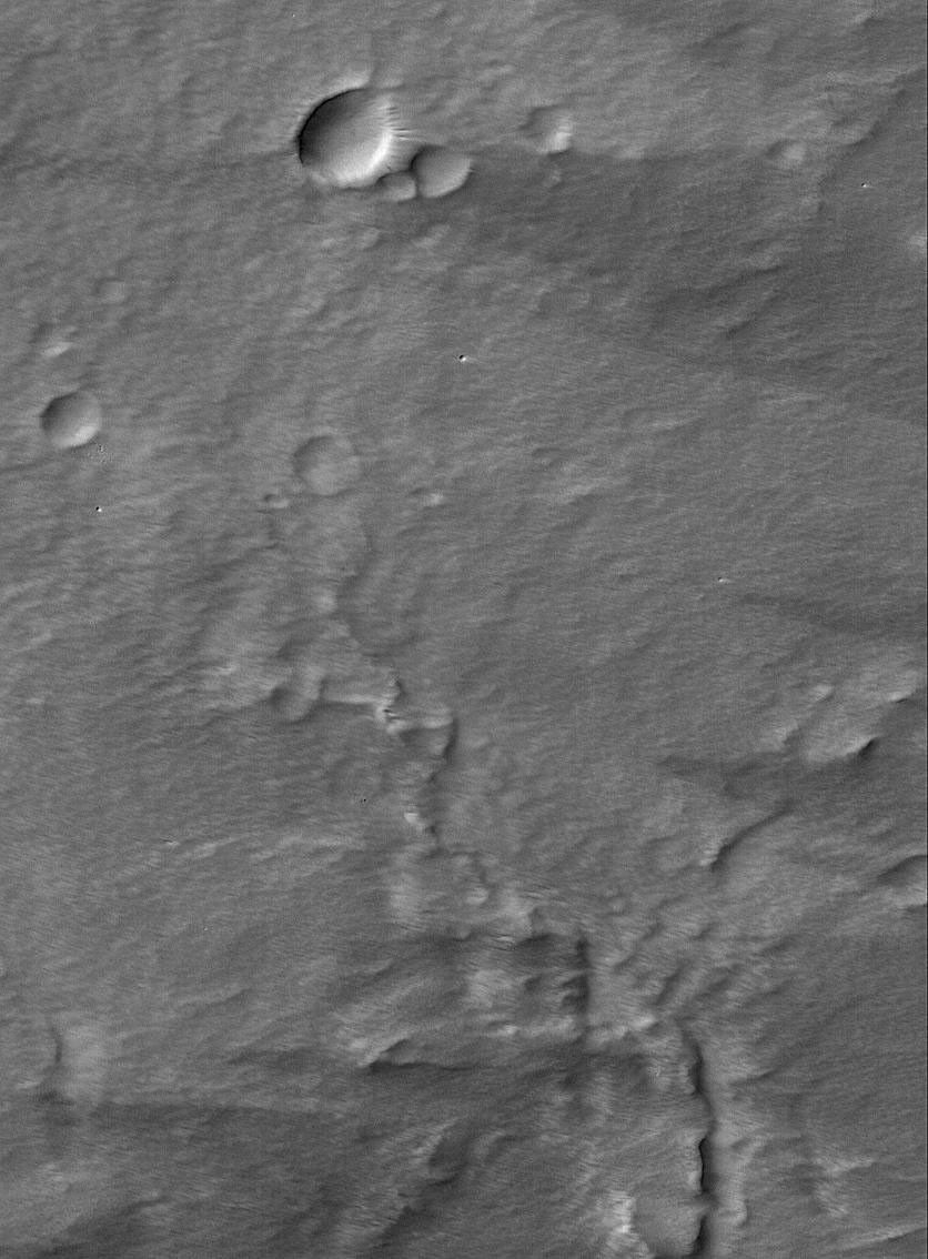 NASA's Mars Global Surveyor shows wind streaks and a thick mantling of dust in the summit region of the martian volcano, Pavonis Mons. Several very small, sharp impact craters are present.