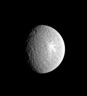 Rhea's distinctive bright and relatively fresh-rayed crater lies in stark contrast to the large, round basin which sits along the terminator (the boundary between day and night) in this unmagnified view from NASA's Cassini spacecraft.