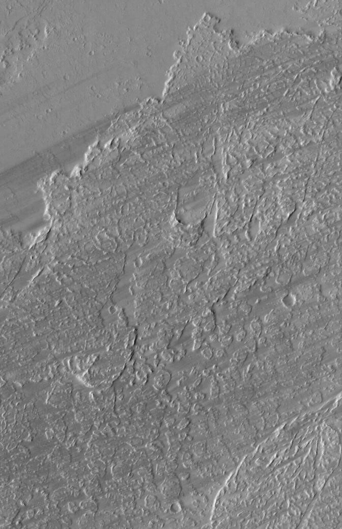 NASA's Mars Global Surveyor shows dark wind streaks streaming across lava flow surfaces in eastern Tharsis, west of the Kasei Valles region of Mars.