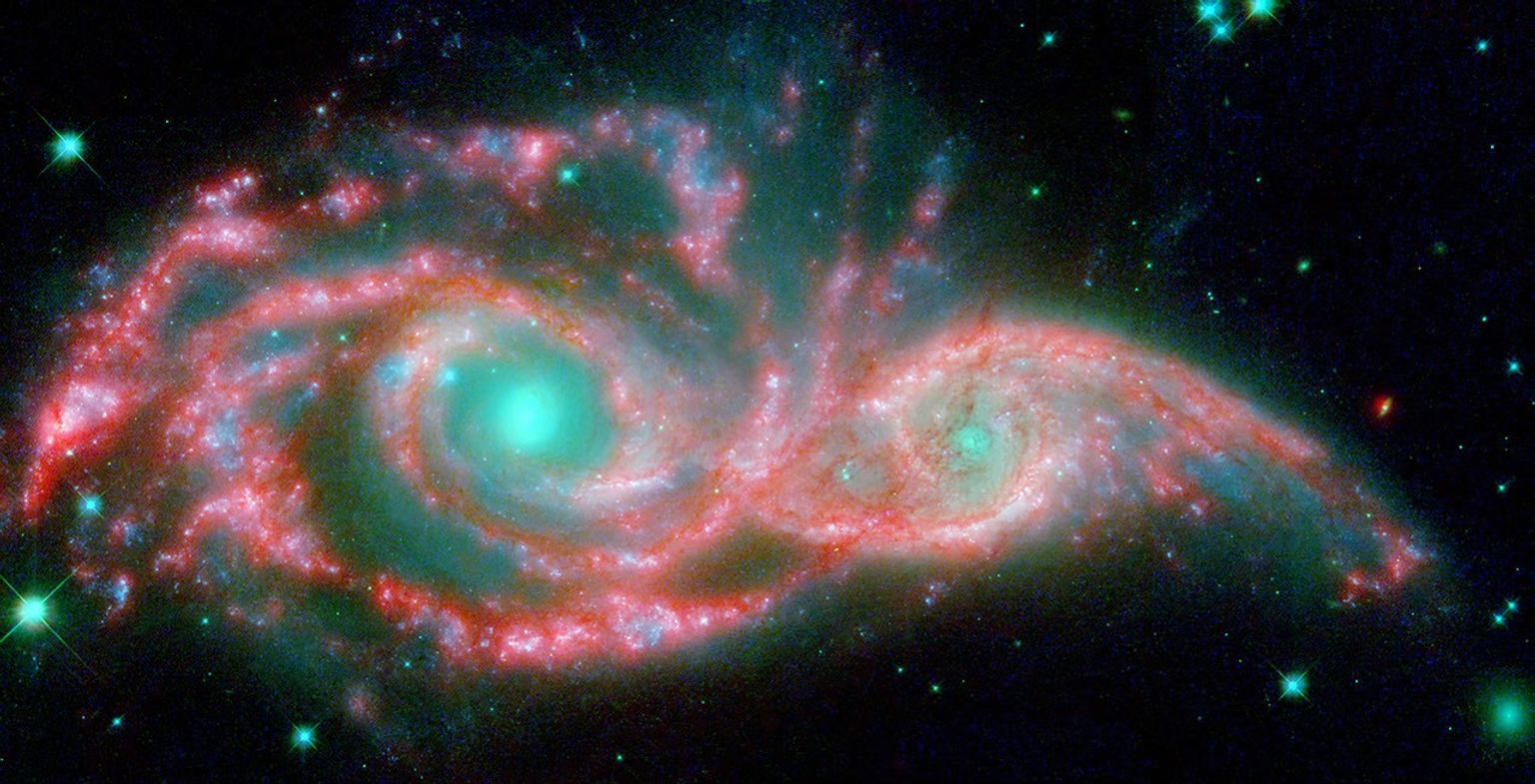 NASA's Hubble and Spitzer telescopes combined to make these shape-shifting galaxies taking on the form of a giant mask. The icy blue eyes are actually the cores of two merging galaxies, called NGC 2207 and IC 2163, and the mask is their spiral arms.