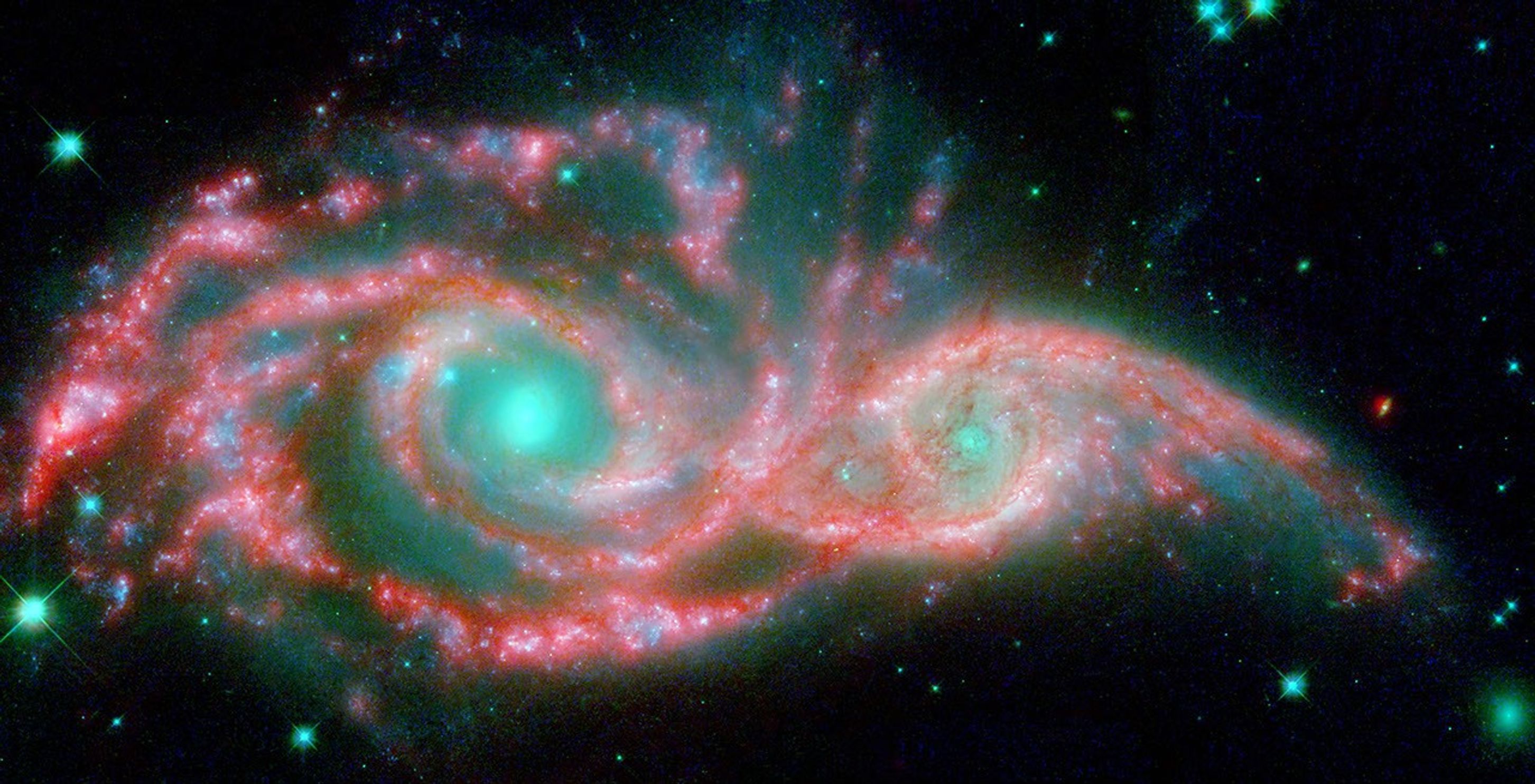NASA's Hubble and Spitzer telescopes combined to make these shape-shifting galaxies taking on the form of a giant mask. The icy blue eyes are actually the cores of two merging galaxies, called NGC 2207 and IC 2163, and the mask is their spiral arms.