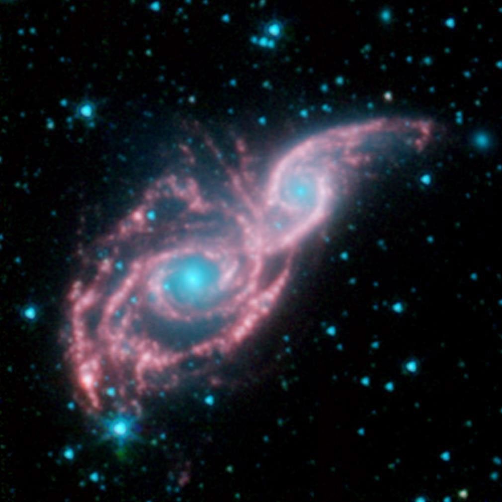 Something appears to be peering through a shiny red mask, in this new false-colored image from NASA's Spitzer Space Telescope. The mysterious blue eyes are actually starlight from the cores of two merging galaxies, called NGC 2207 and IC 2163.