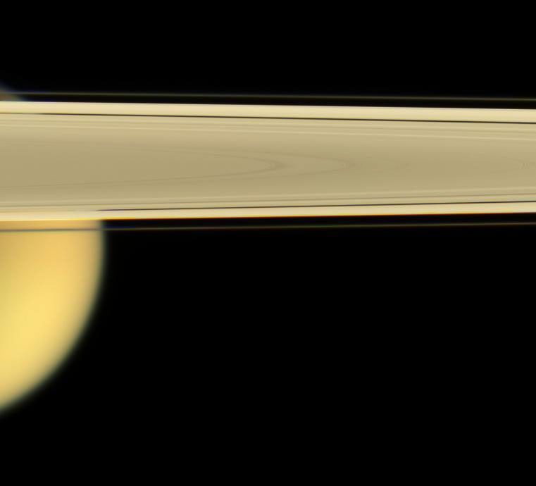 Saturn's largest moon, Titan, peaks out from under the planet's rings of ice in this image from NASA's Cassini spacecraft taken on April 28, 2006.