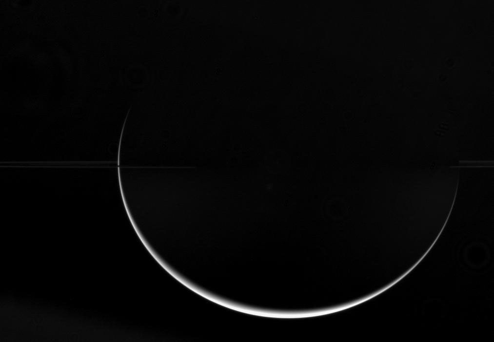 Saturn's low density and fast rotation combine to give it its characteristic oblate shape. The dramatic crescent captured by NASA's Cassini spacecraft demonstrates how the ringed planet is much wider at the equator than at the poles.