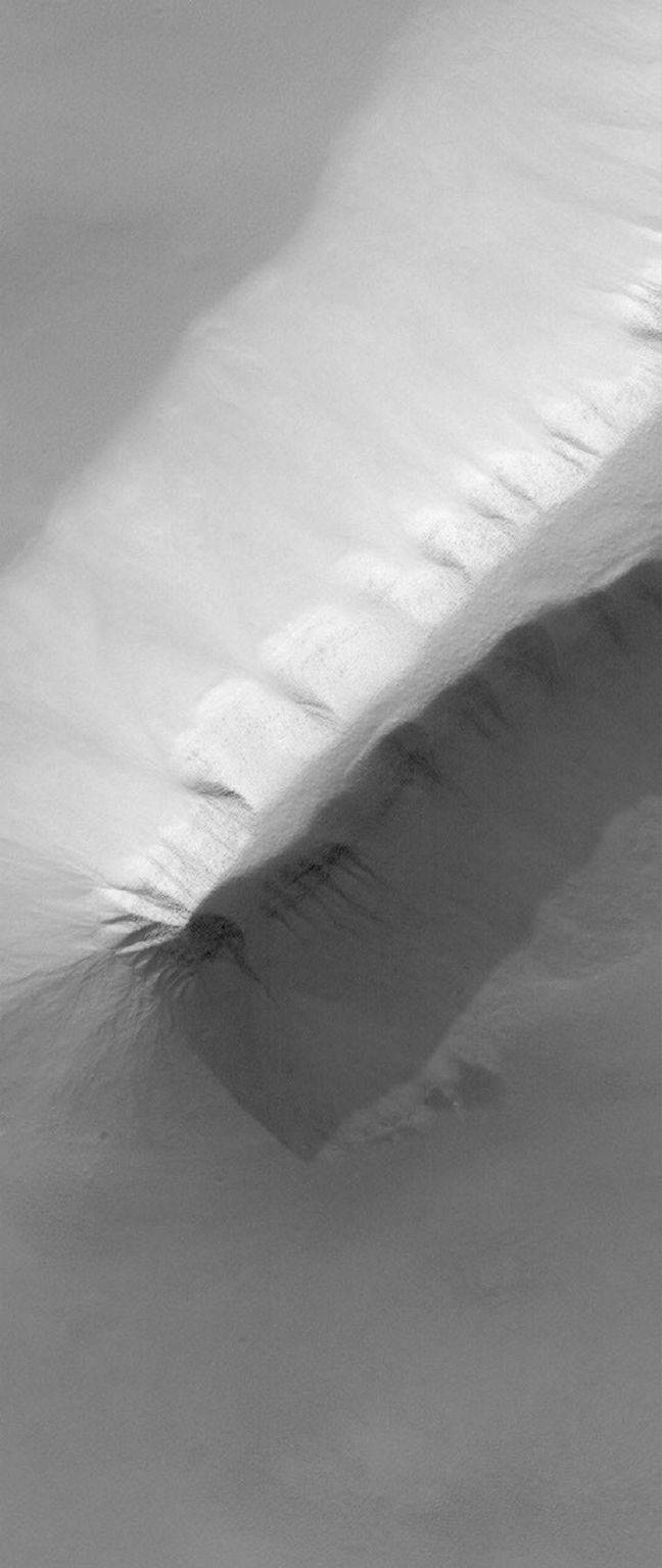 NASA's Mars Global Surveyor shows a spine of material exposed in the Sisyphi Planum region of Mars. Gullies can be seen on the deeply-shadowed ridge slope.