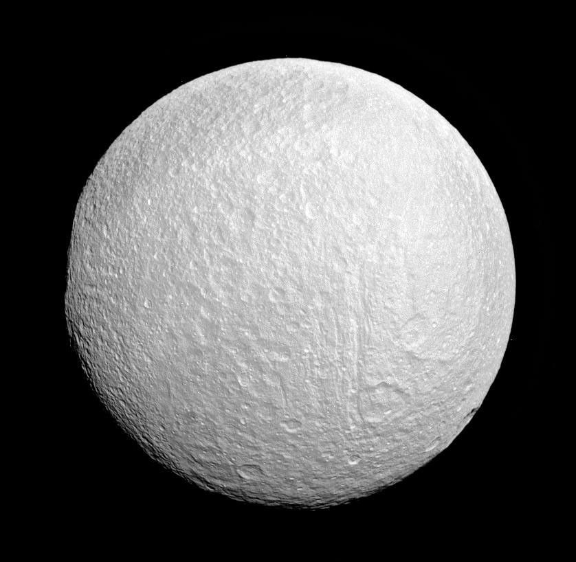 Ithaca Chasma rips across Saturn's moon Tethys from north to south near the center of this view from NASA's Cassini spacecraft. The moon's western limb is flattened, indicating the rim of the giant impact basin Odysseus.