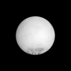 Enceladus appears as a rather bland orb in this far-off snapshot, but the dark markings, called sulci, long, roughly parallel fractures from which a spray of icy particles escapes into the void, are seen by NASA's Cassini spacecraft.