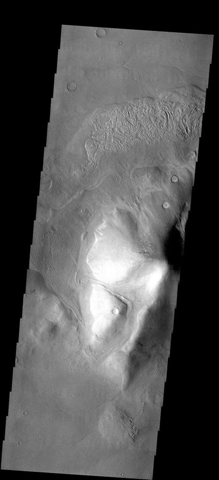 This image from NASA's Mars Odyssey spacecraft shows an isolated hill located south of Reull Vallis on the eastern margin of Hellas Basin. Material from the hill is collecting at the base of the hill.
