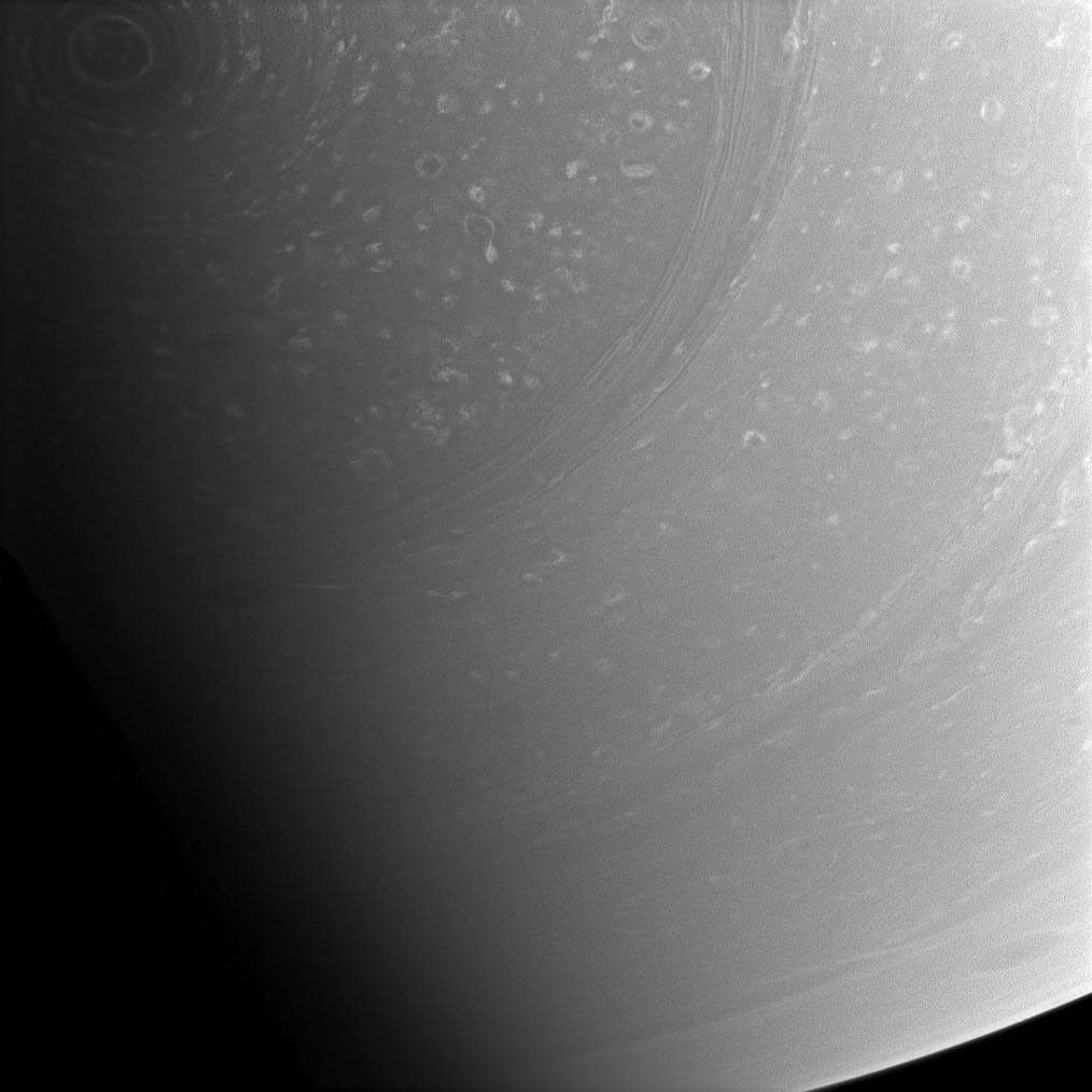 The hurricane-like vortex encircling Saturn's south pole is still visible in the top left of this image as it slowly slips into darkness with the planet's changing seasons. This image was taken with NASA's Cassini spacecraft's wide-angle camera.