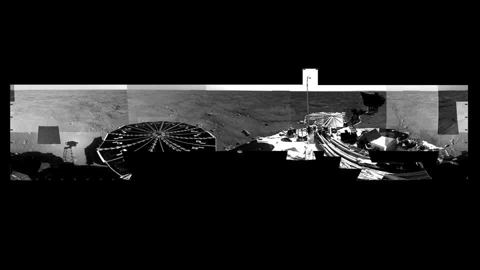 NASA's Phoenix Mars Lander sees its shadow and turns its head viewing solar arrays, the lander deck and landscape on the polar arctic of Mars. Very few rocks are present on the hummocky terrain and network of troughs.