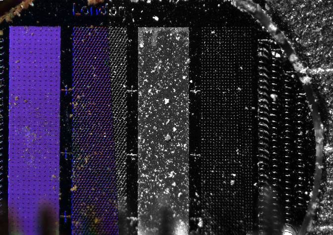 This image from NASA's Phoenix Mars Lander on June 11, 2008, shows soil sprinkled from the lander's Robot Arm scoop onto a substrate micromachined to produce different patterns of pegs and holes to capture the smallest particles in the Martian soil.