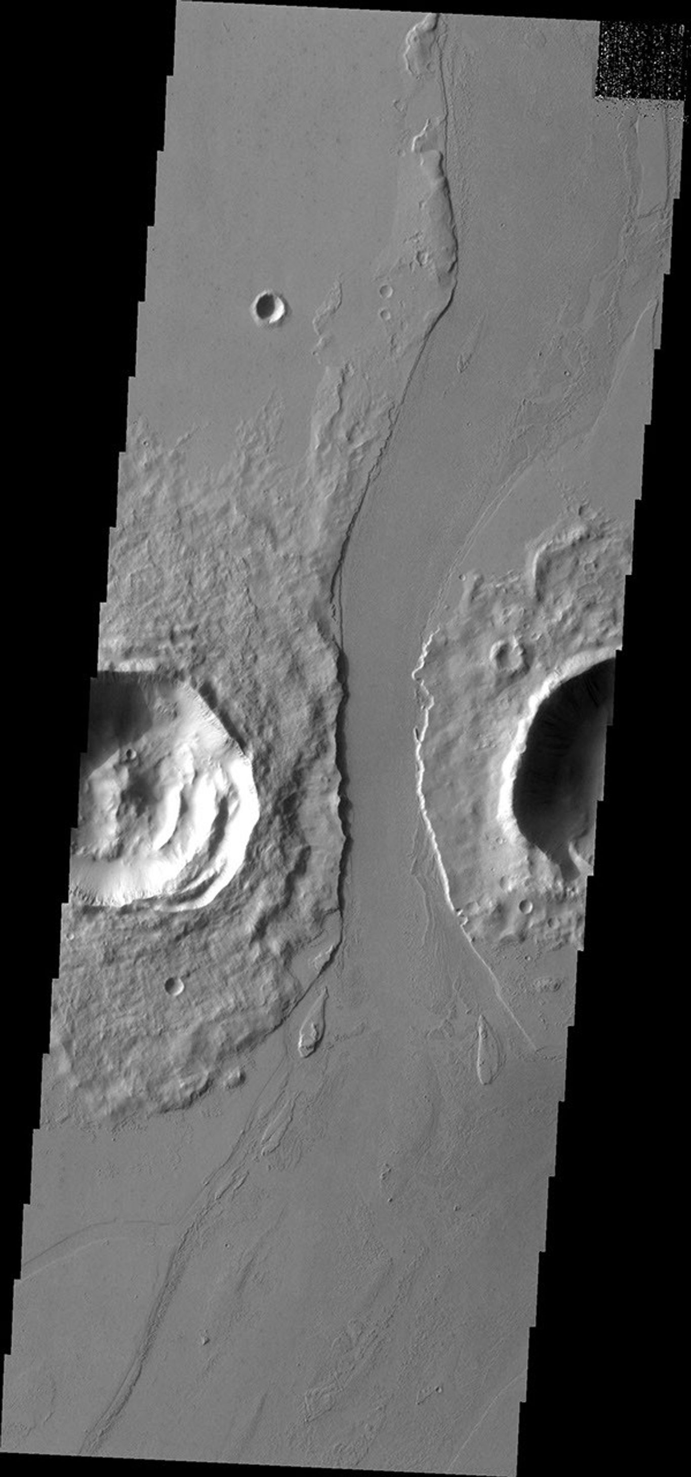 This image from NASA's Mars Odyssey shows a lava channel that cuts between these two craters in Marte Valles.