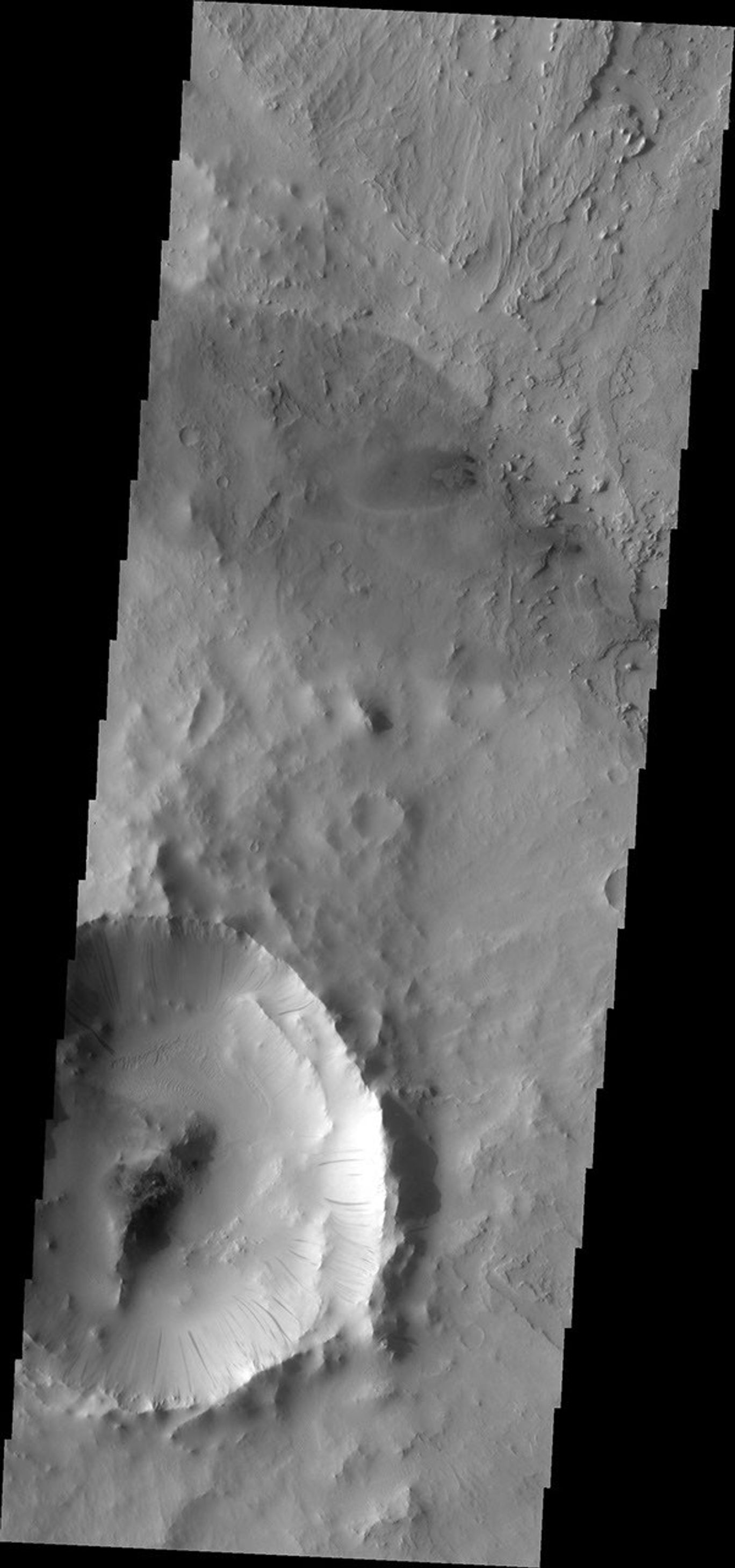 This image from NASA's Mars Odyssey shows numerous dark slope streaks marking the inner rim of this small impact crater within Tikhonravov Crater. Just to the north of the small crater are several small sand dunes.