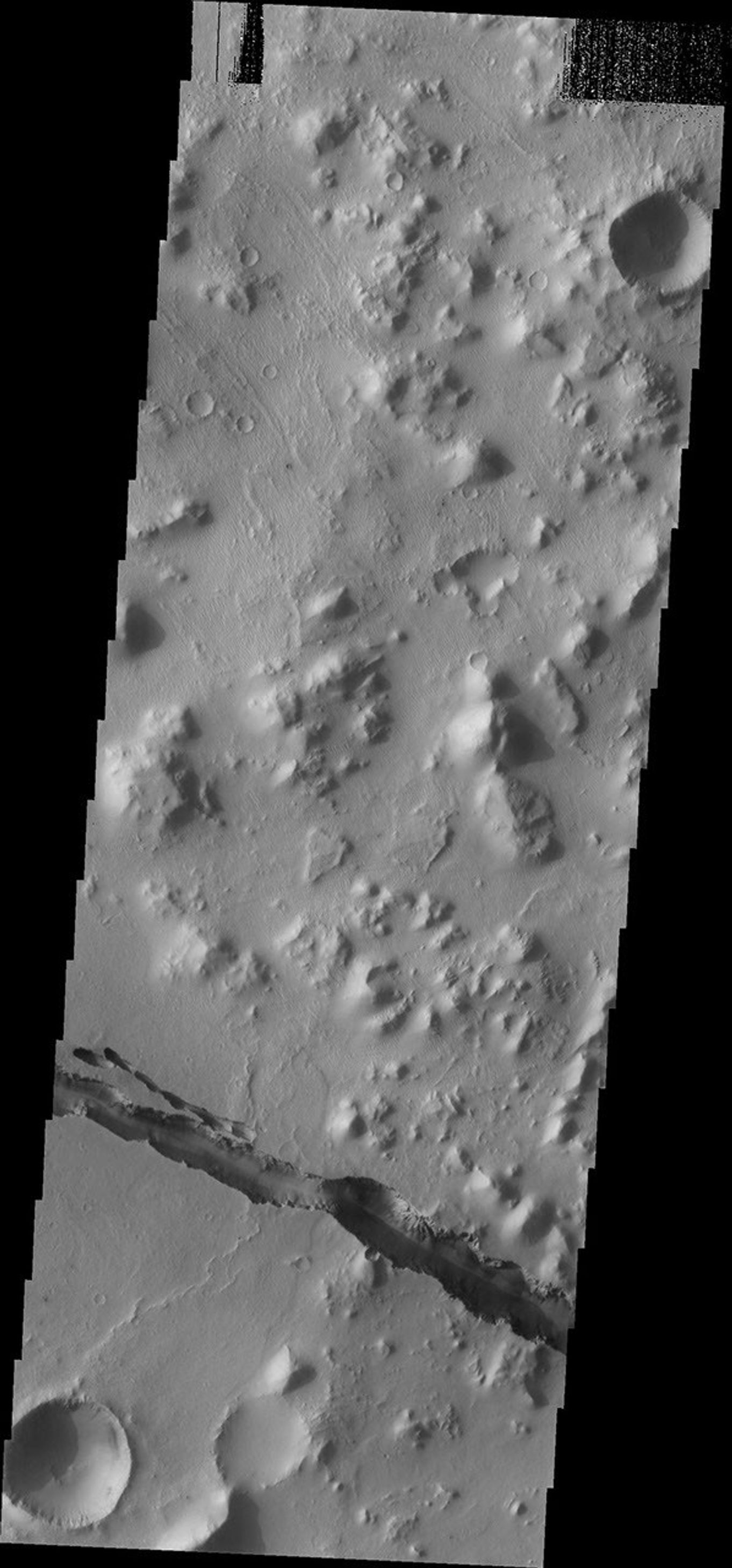 This image from NASA's Mars Odyssey shows a depression that is part of the fracture system called Cerberus Fossae on Mars. The fossae cut through hills as well as plains materials.